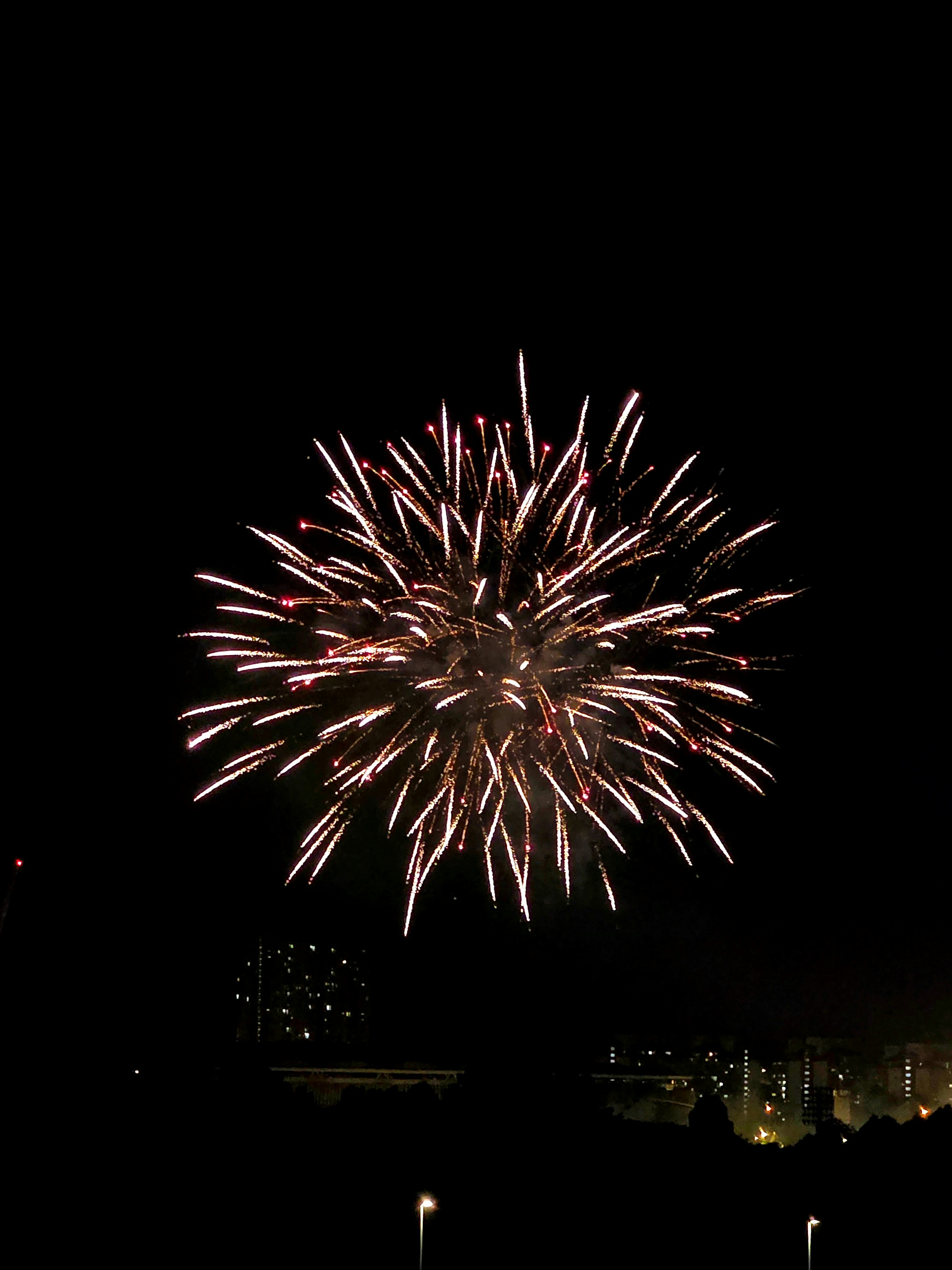White fireworks explode brightly in the dark night sky.