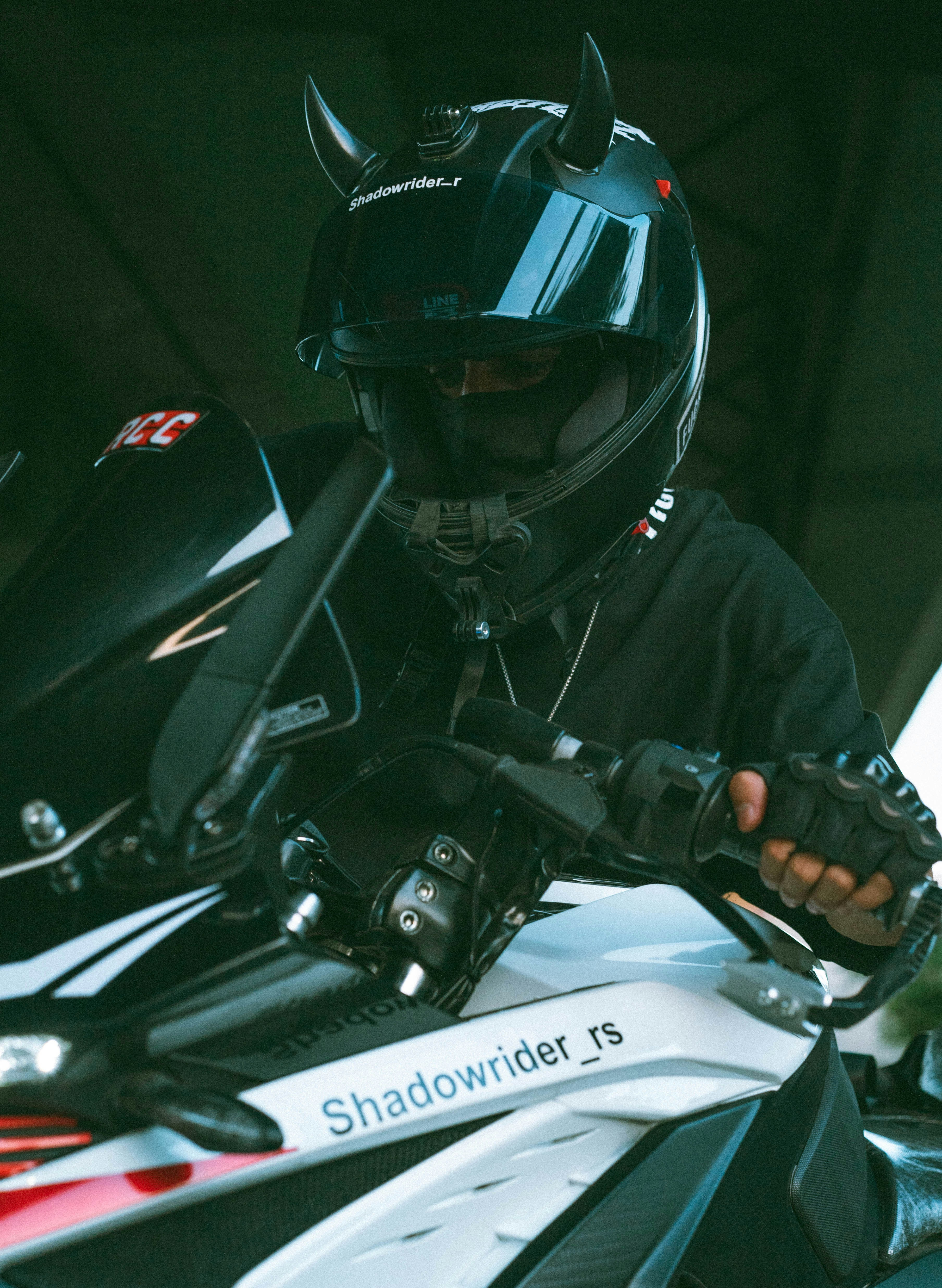 Pessoa com capacete preto e chifres de diabo em uma motocicleta.
