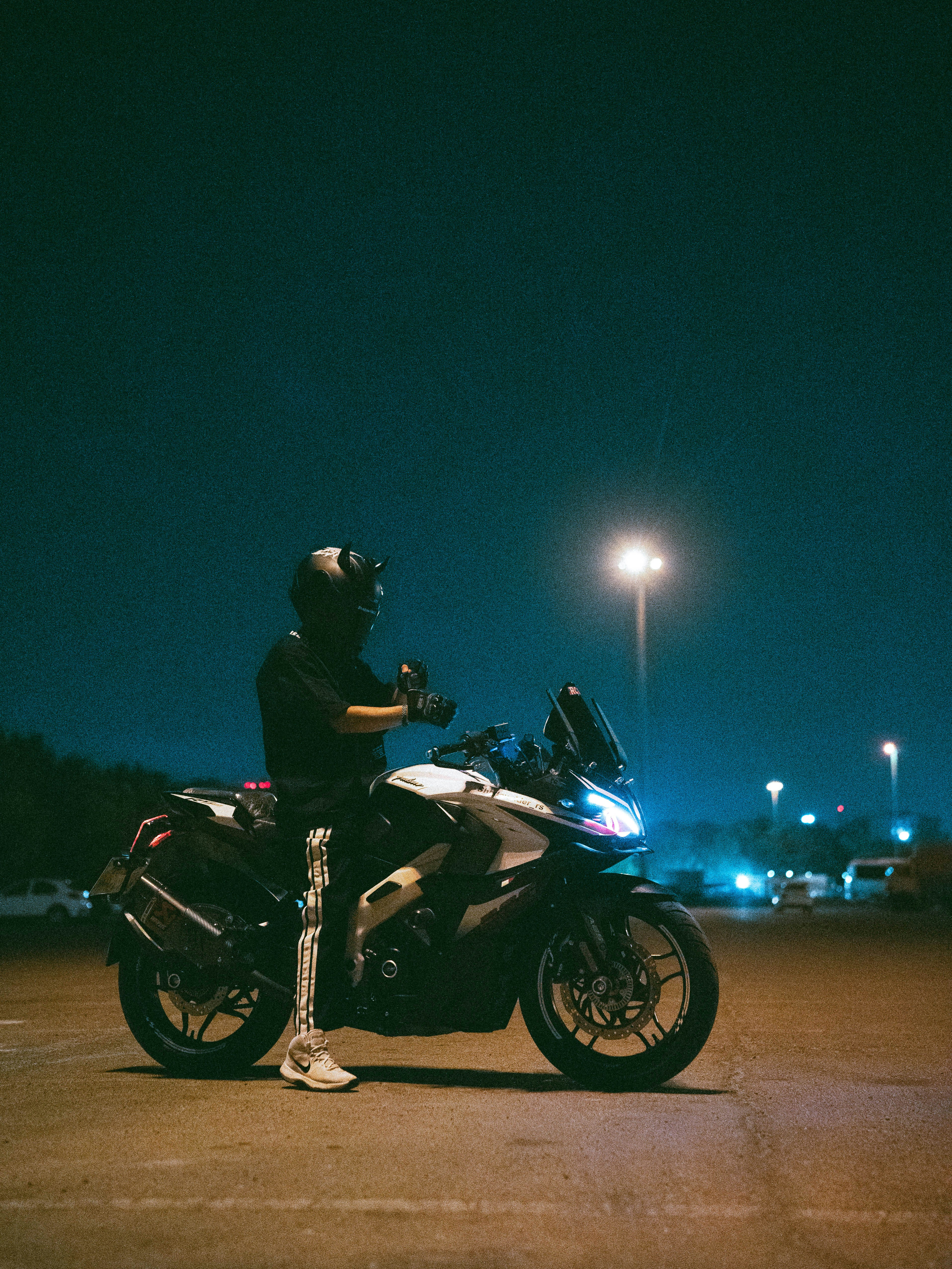 Motociclista em uma moto à noite sob postes de luz.