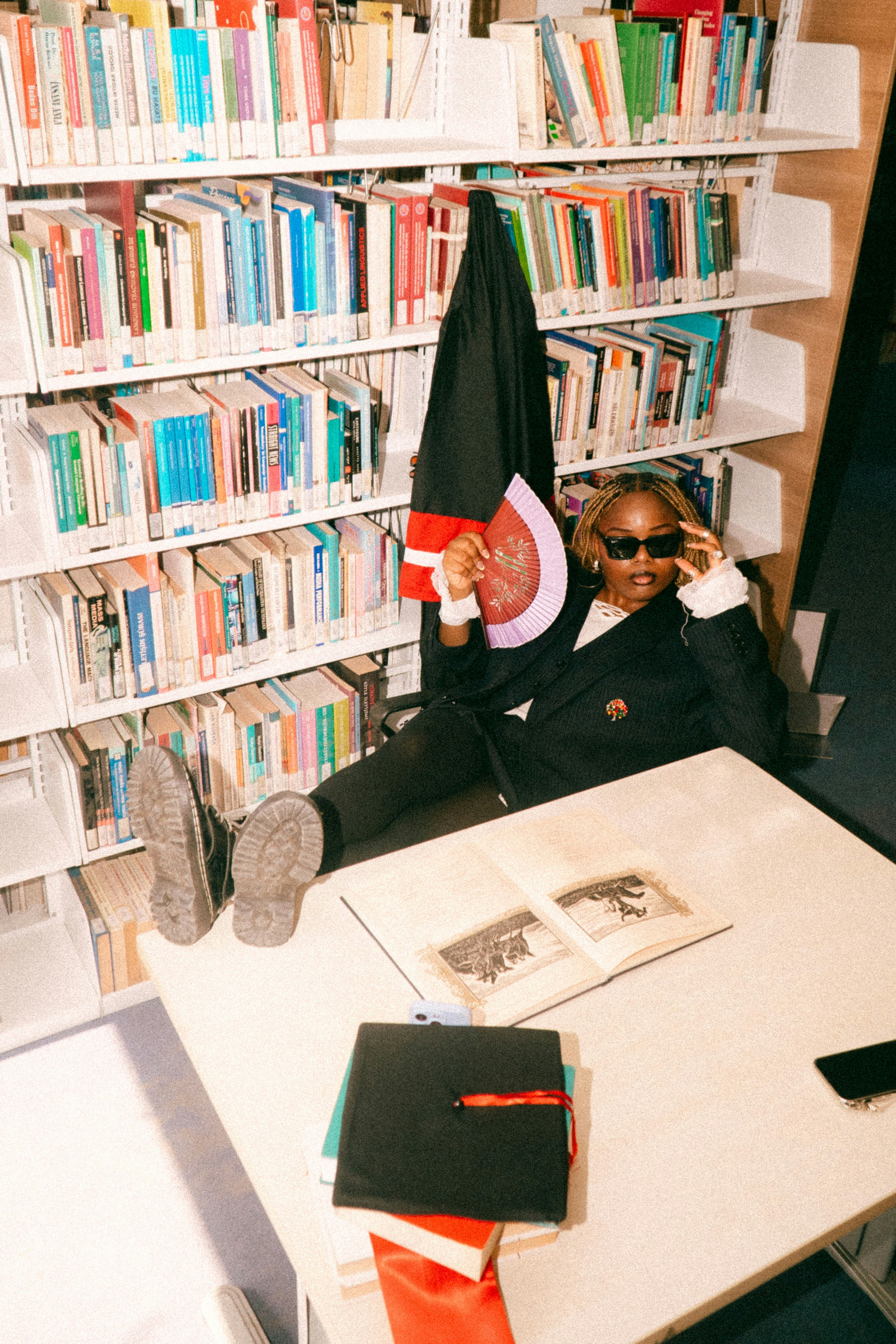 スーツ姿でサングラスをかけた人が図書館でくつろぐ様子