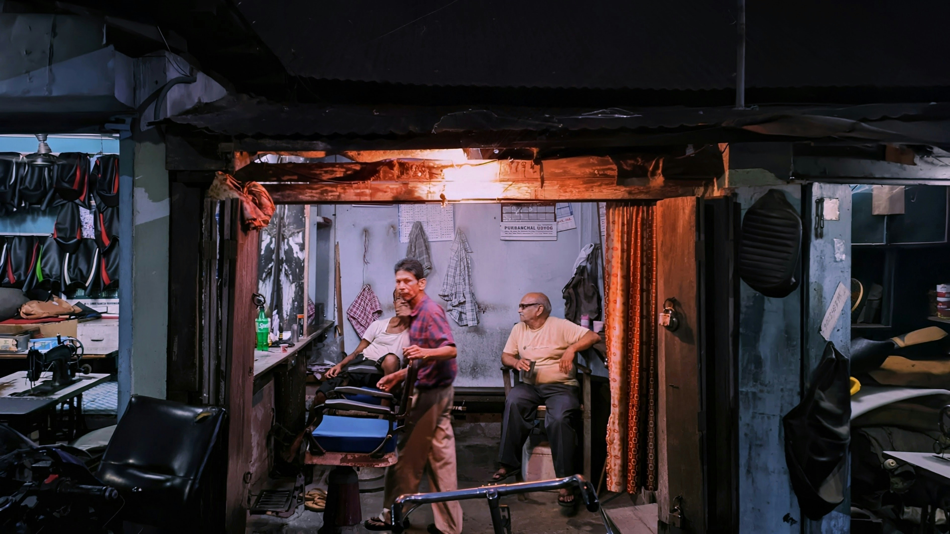 Kırklareli Berber Tavsiye: 18 İşletme, 655 Yoruma Göre Nasıl Seçilir? — Two men in a dimly lit barbershop with a single warm overhead light