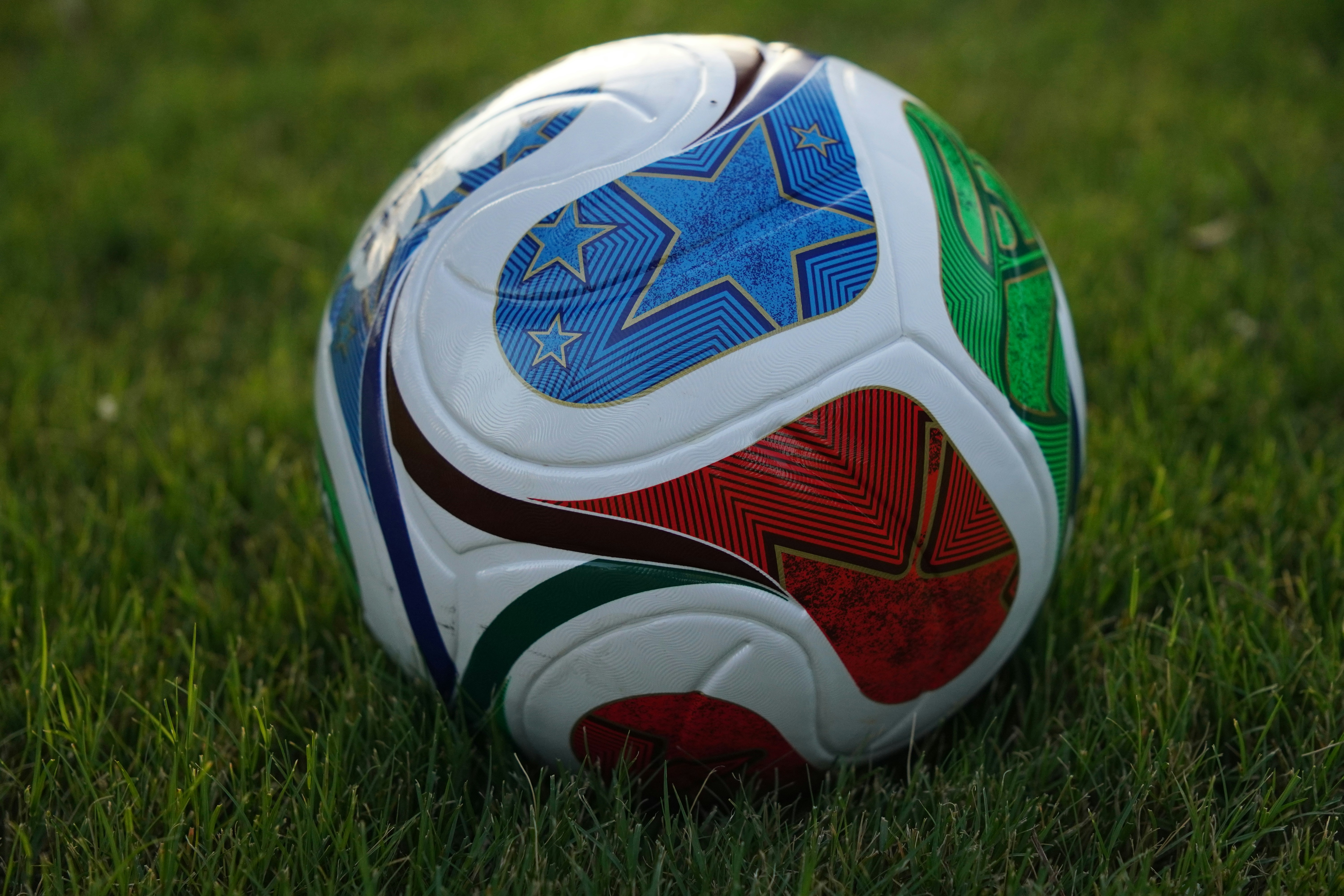 A colorful soccer ball rests on green grass.