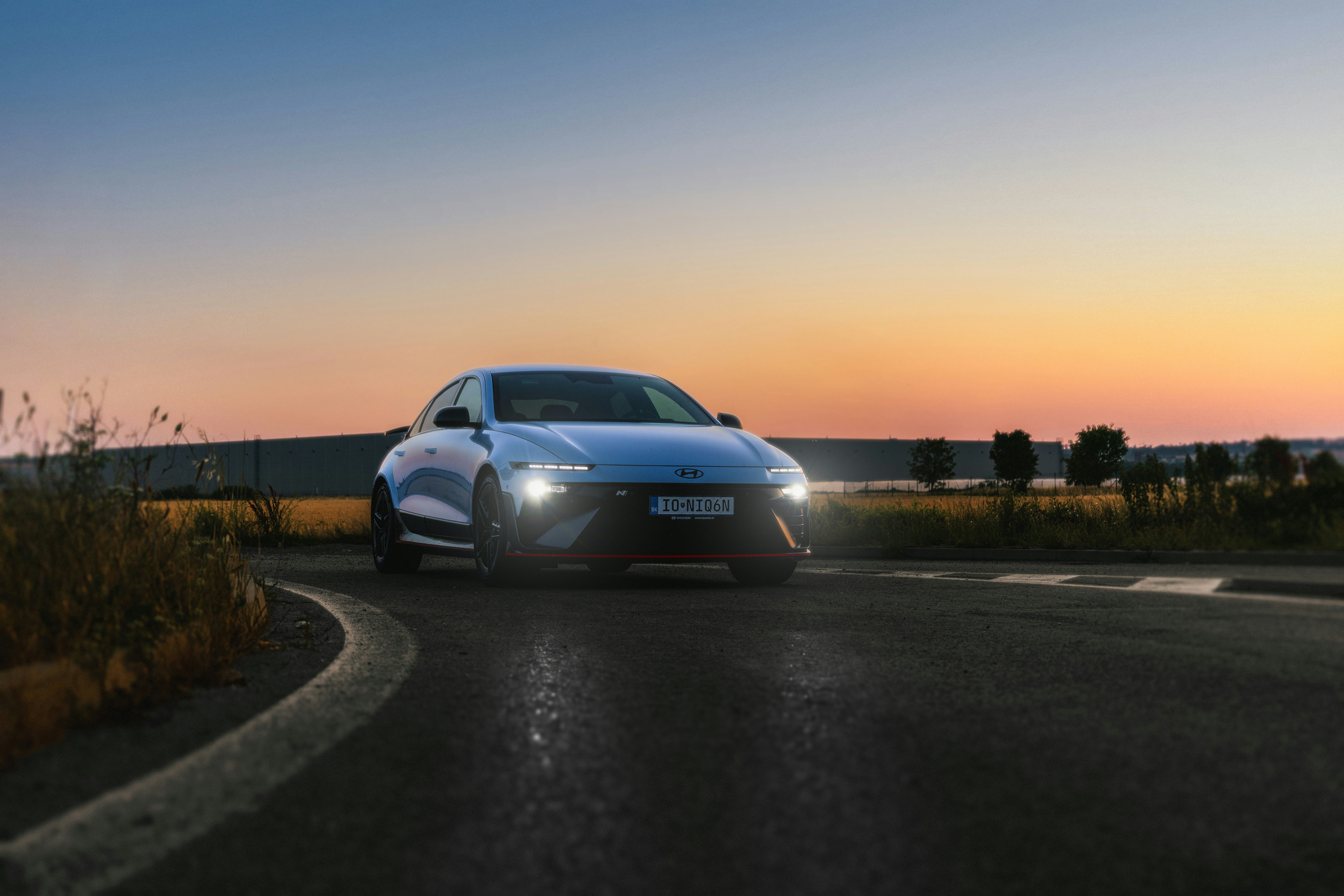 A modern blue car on a road at sunset.