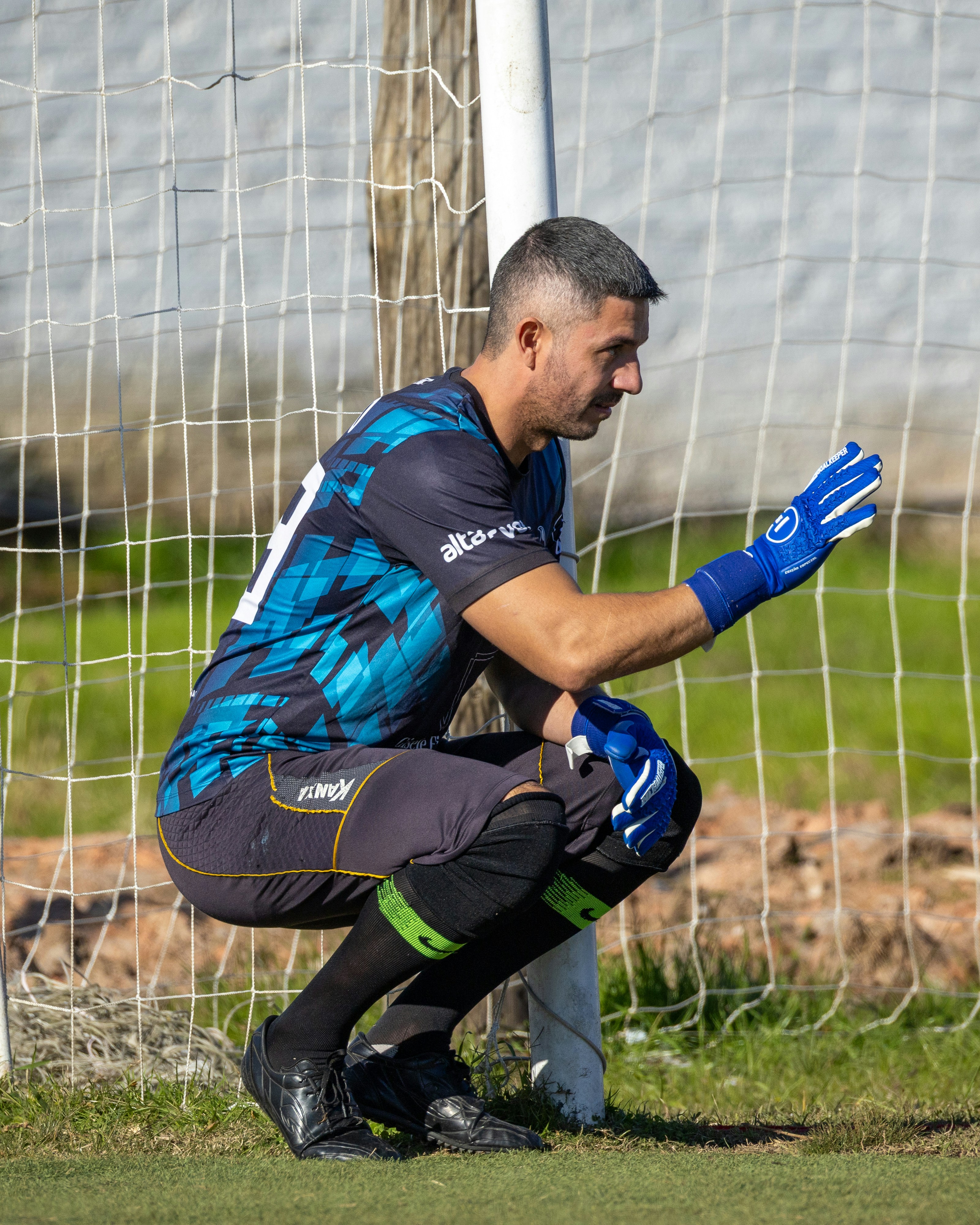 A soccer goalkeeper crouches in front of the goal net