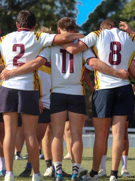 Three athletes with arms around shoulders on a sports field.