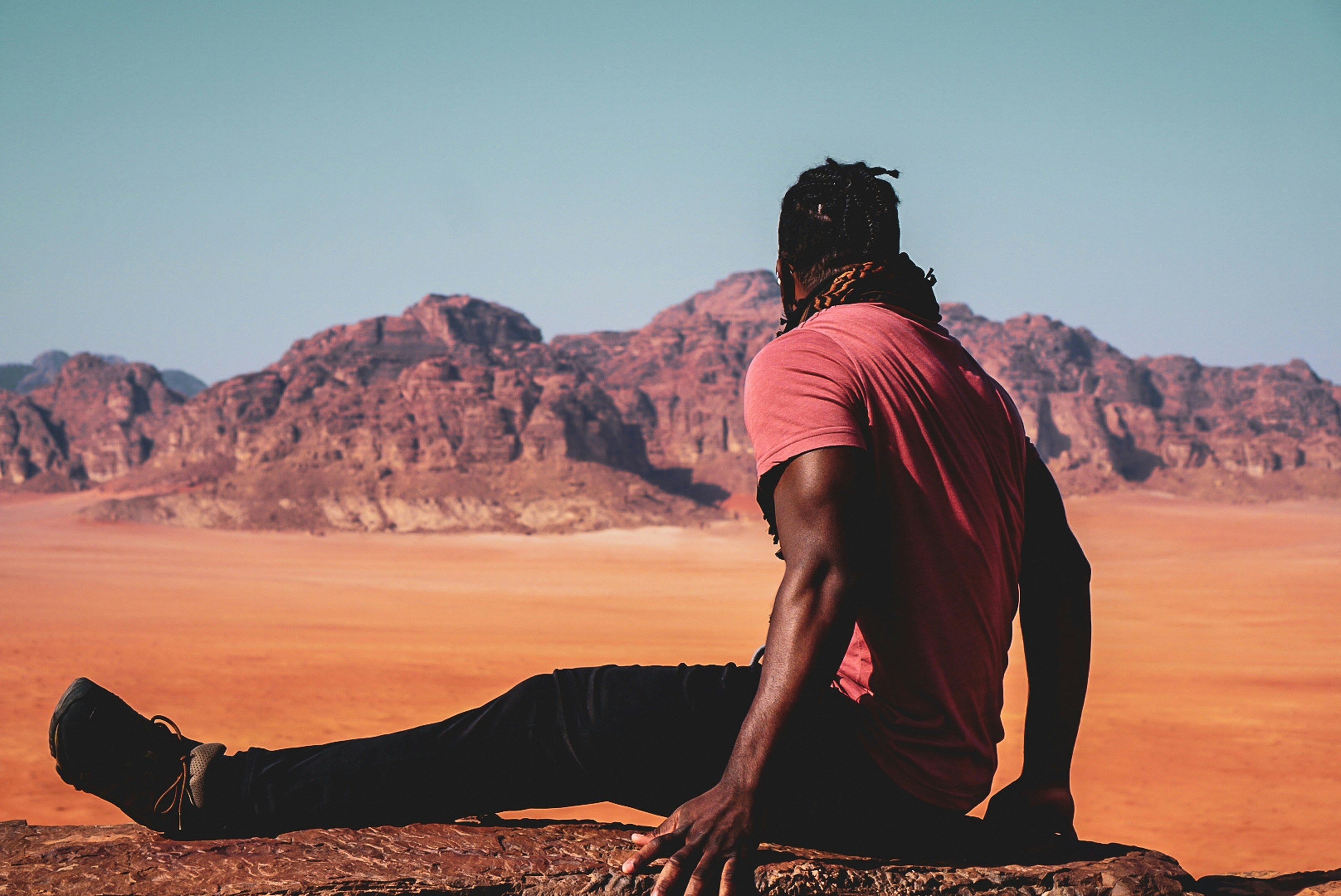 Person sits overlooking a vast desert landscape with mountains