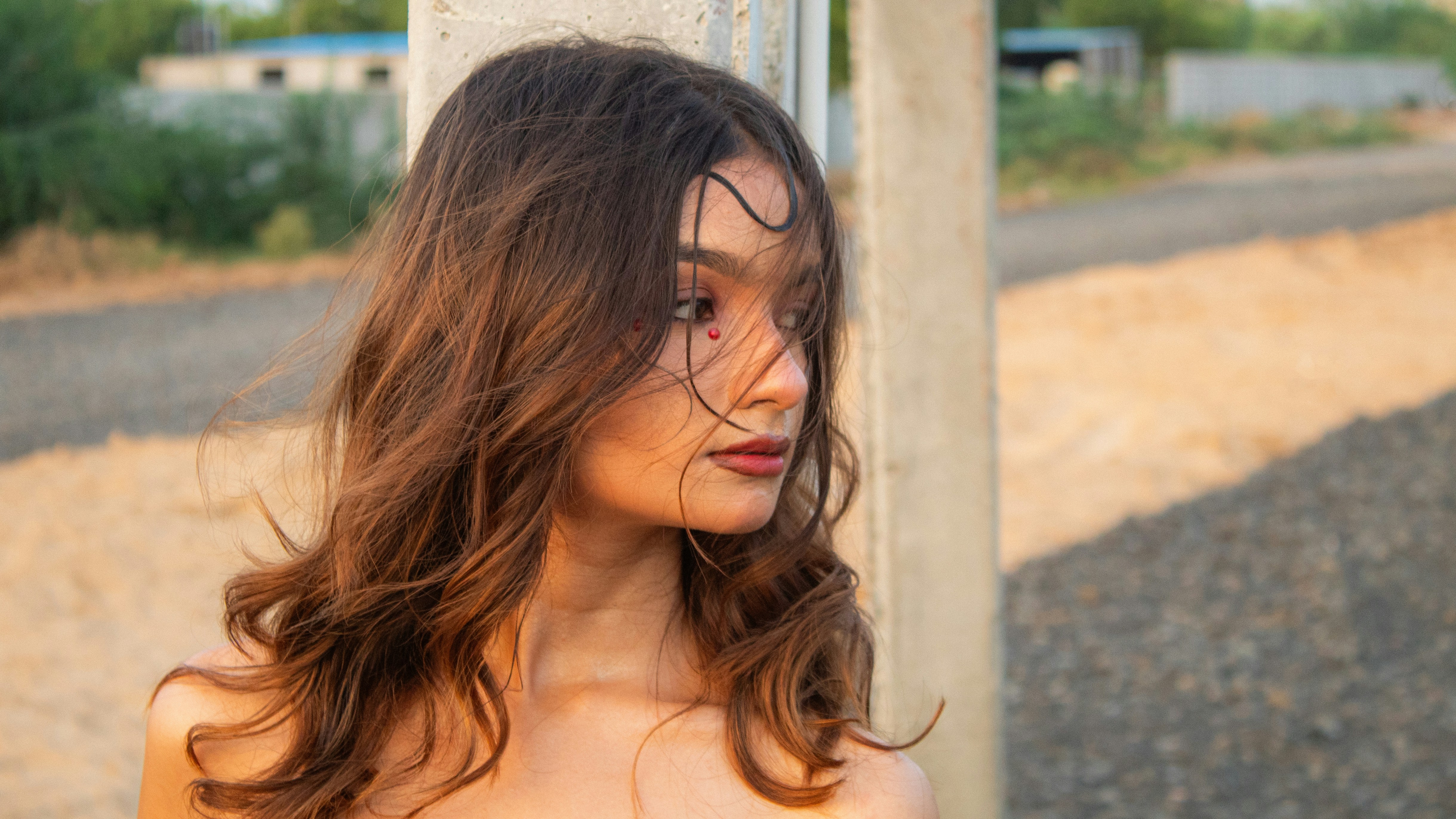 Young woman with wavy hair and red lips looks right
