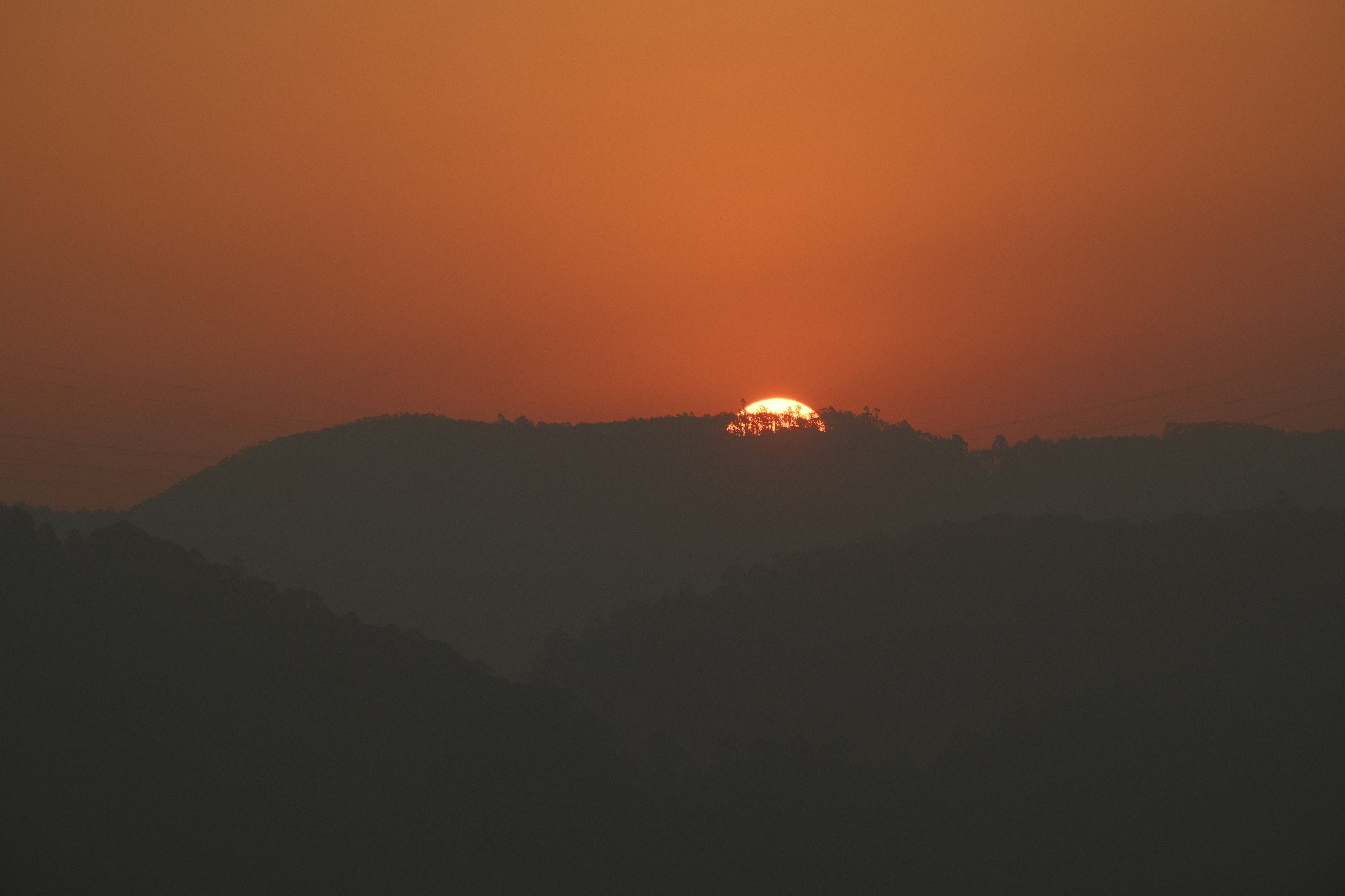 Orange sunset behind silhouetted mountains.