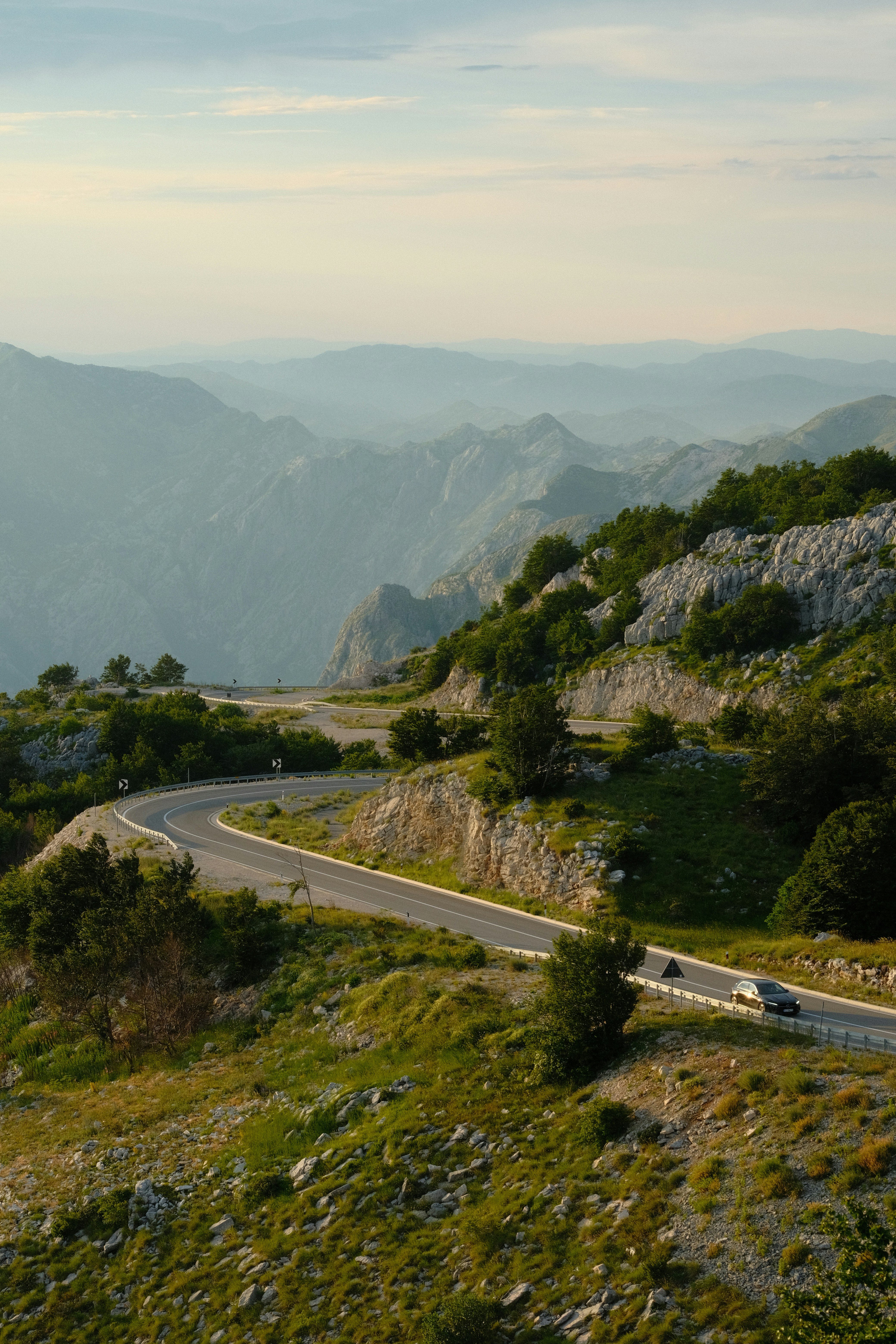 Une route sinueuse serpente à travers des montagnes vertes avec une voiture