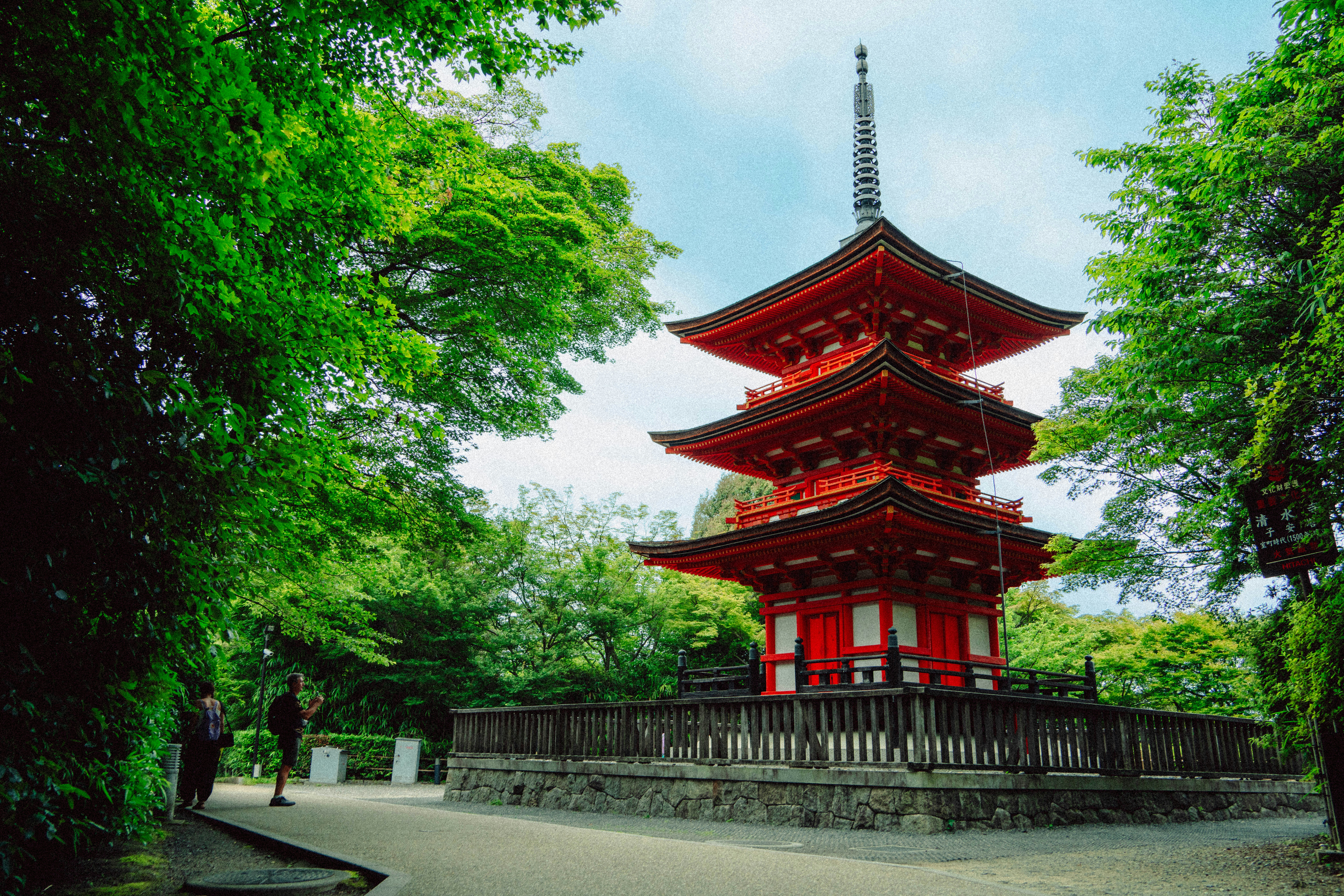 A red pagoda stands amidst lush green trees.