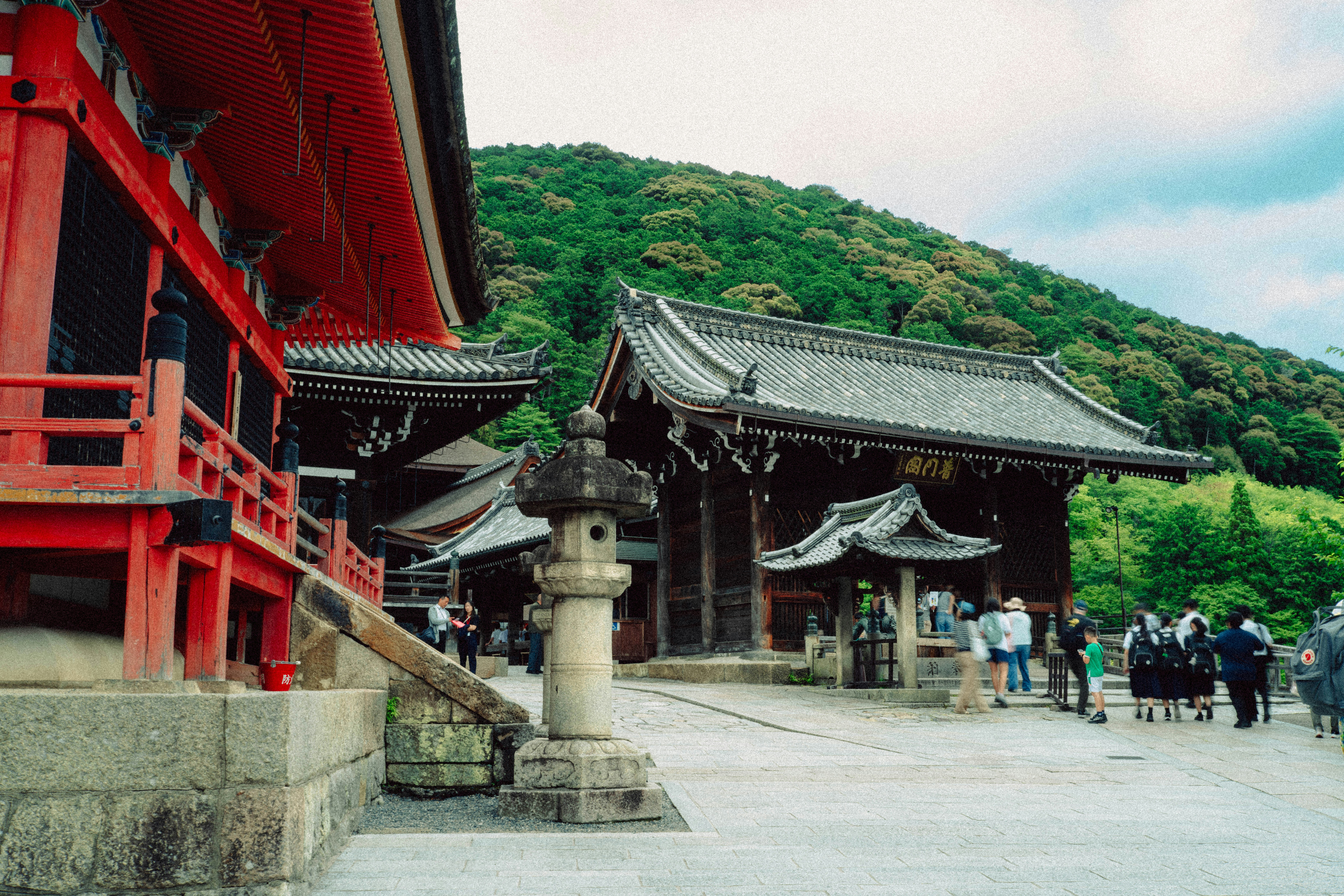 Traditional japanese temple complex with red buildings and green mountains.