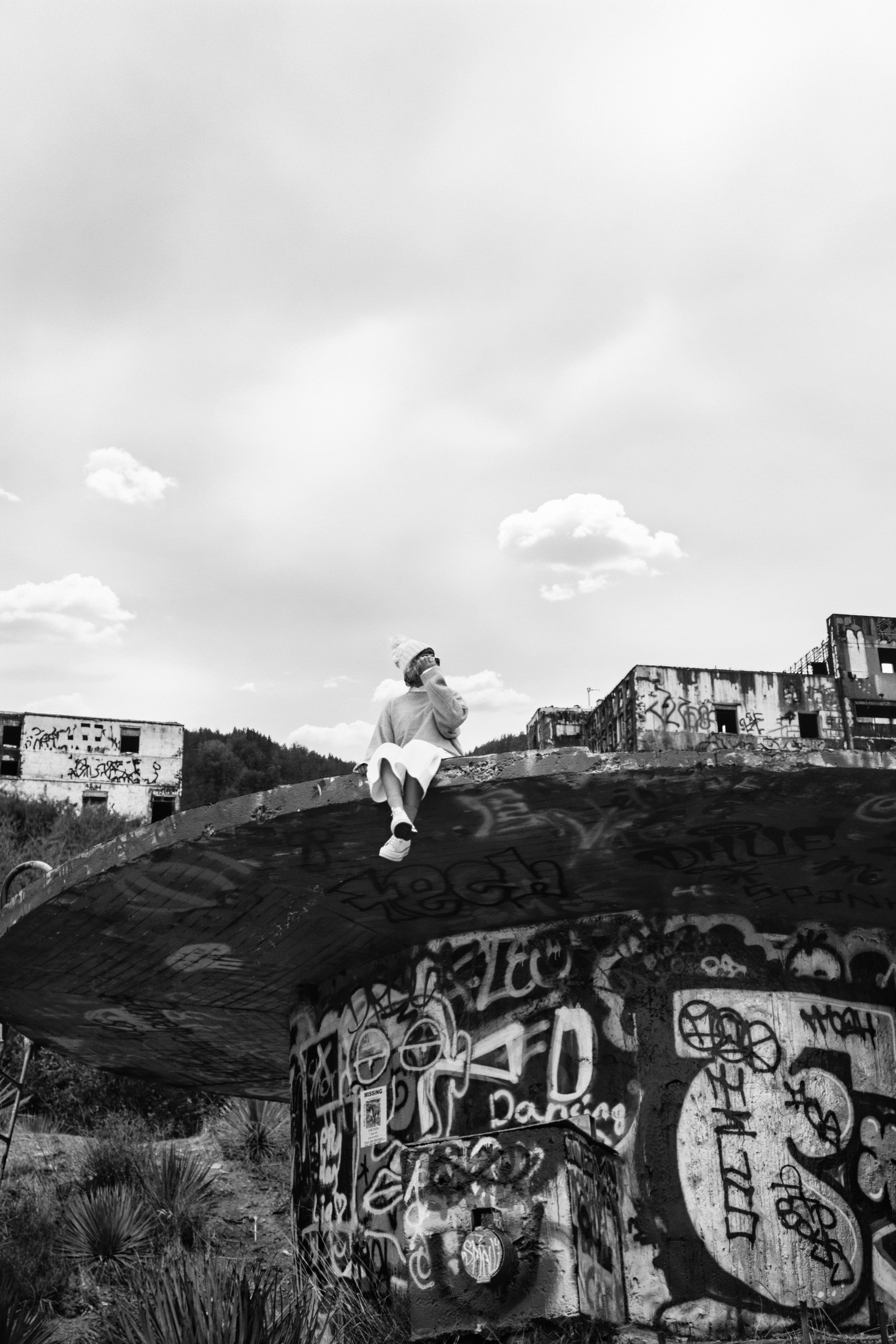Personne assise sur une structure en béton couverte de graffitis