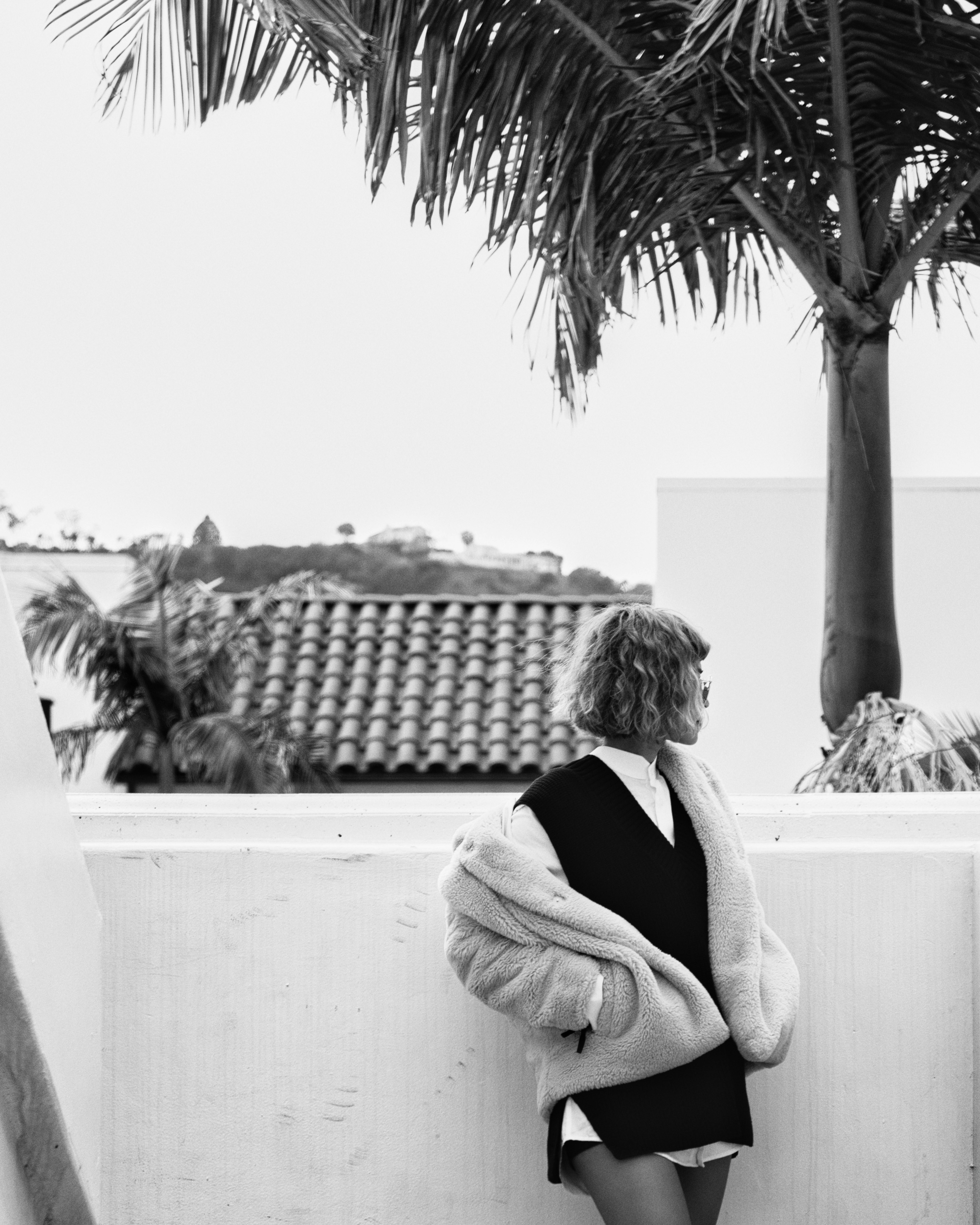 Femme en veste sur la terrasse avec un palmier