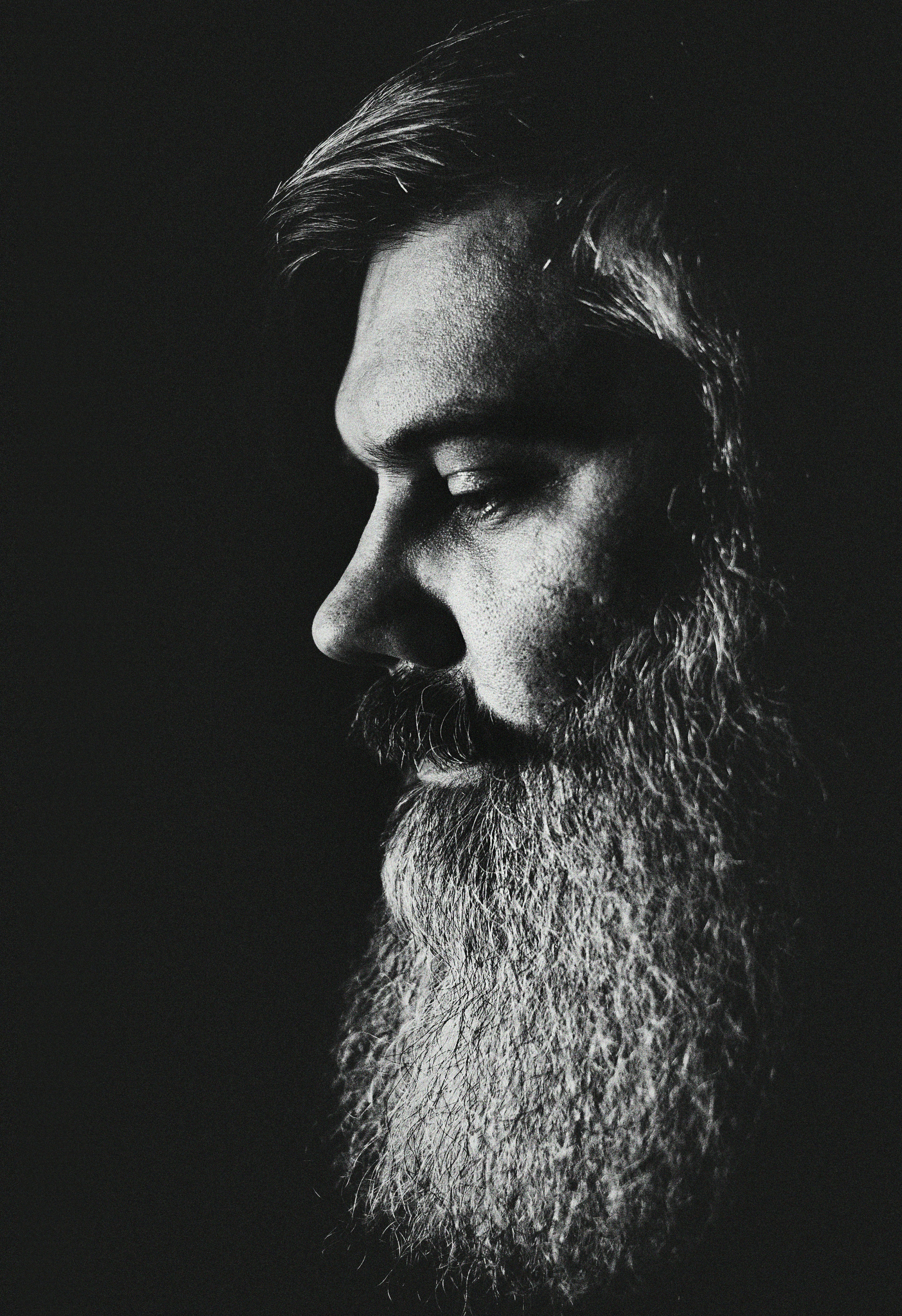 Black and white profile of a bearded man looking down.