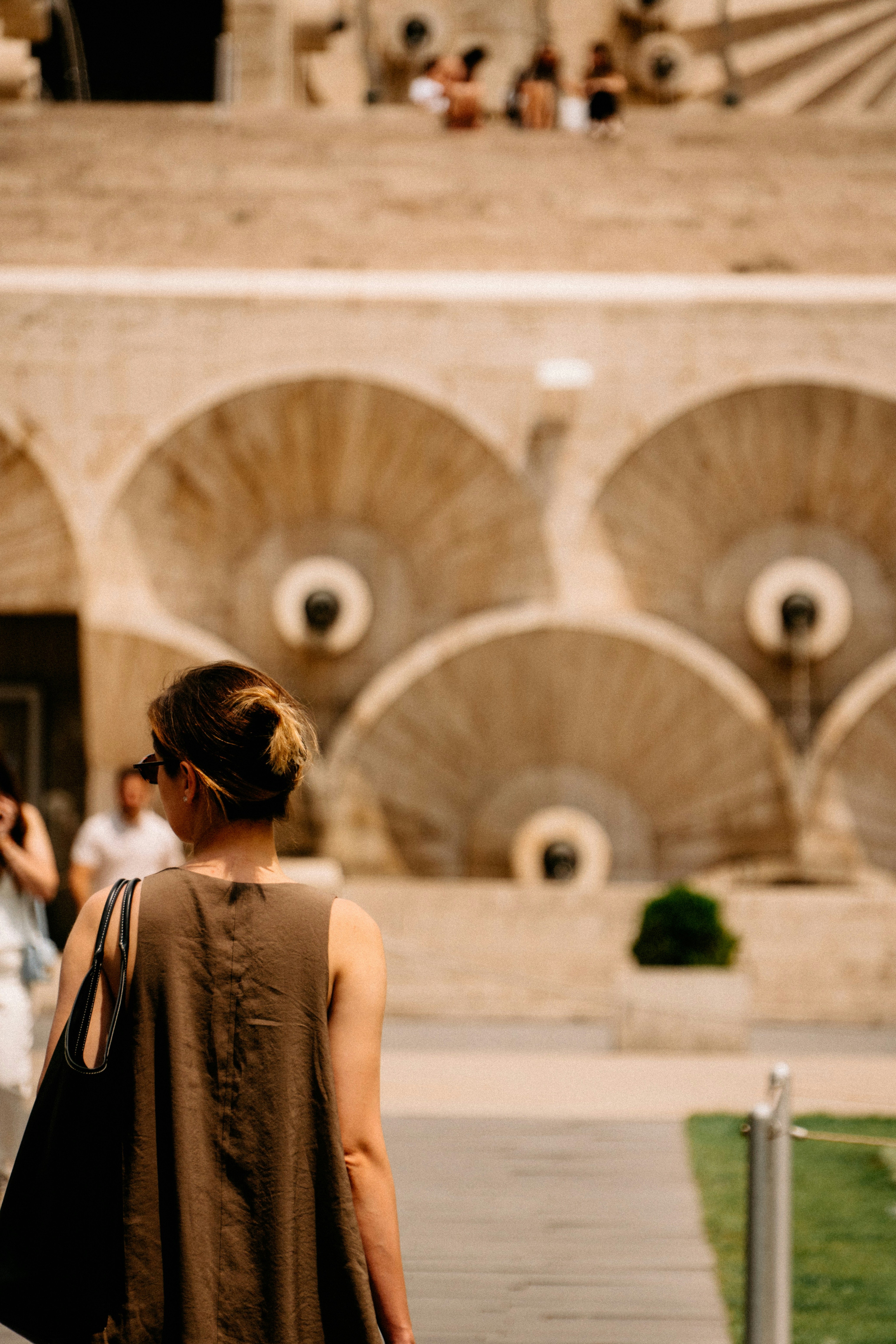 Woman walking past an ornate stone cascade with people above