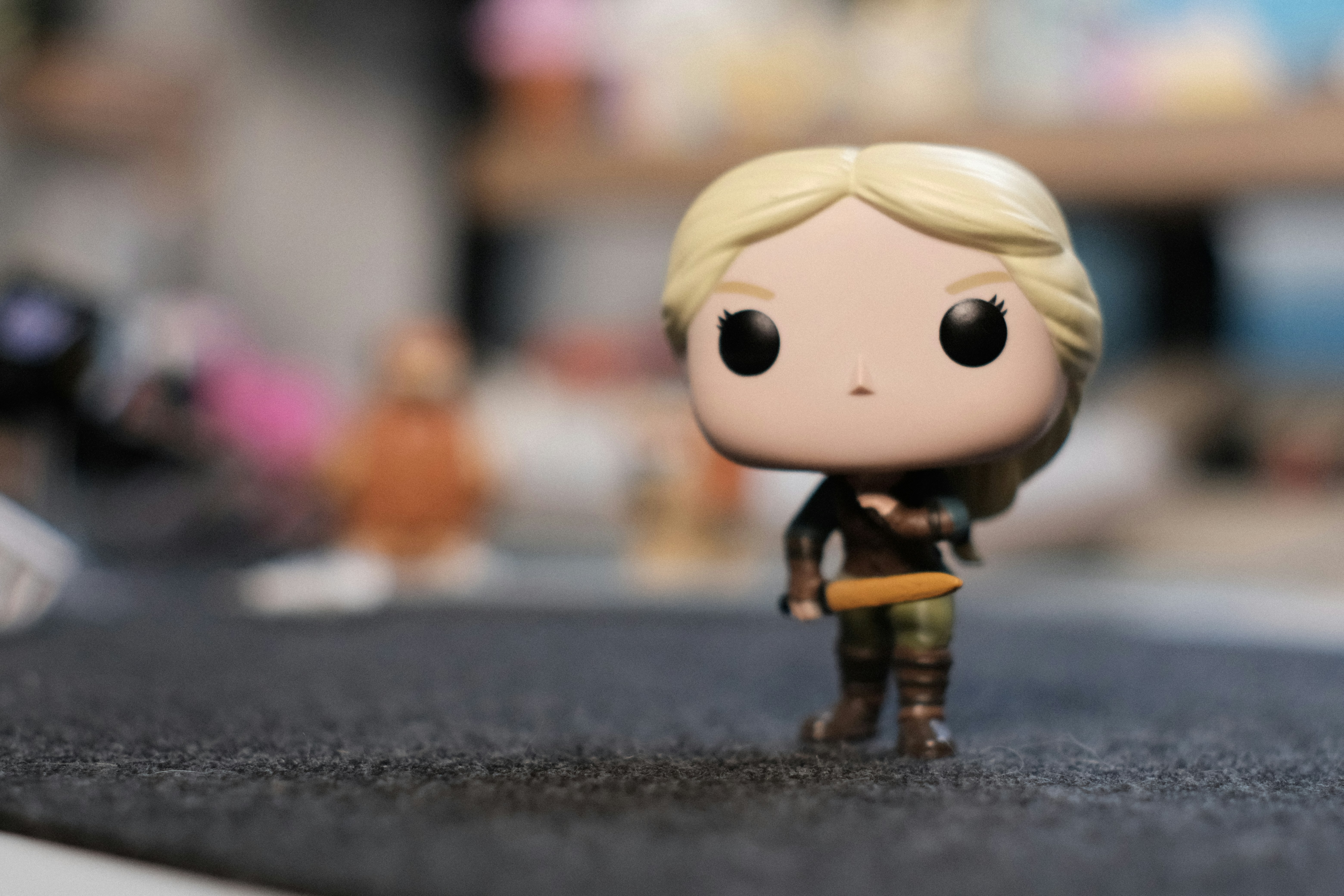 Blonde woman funko pop figure standing on dark surface.