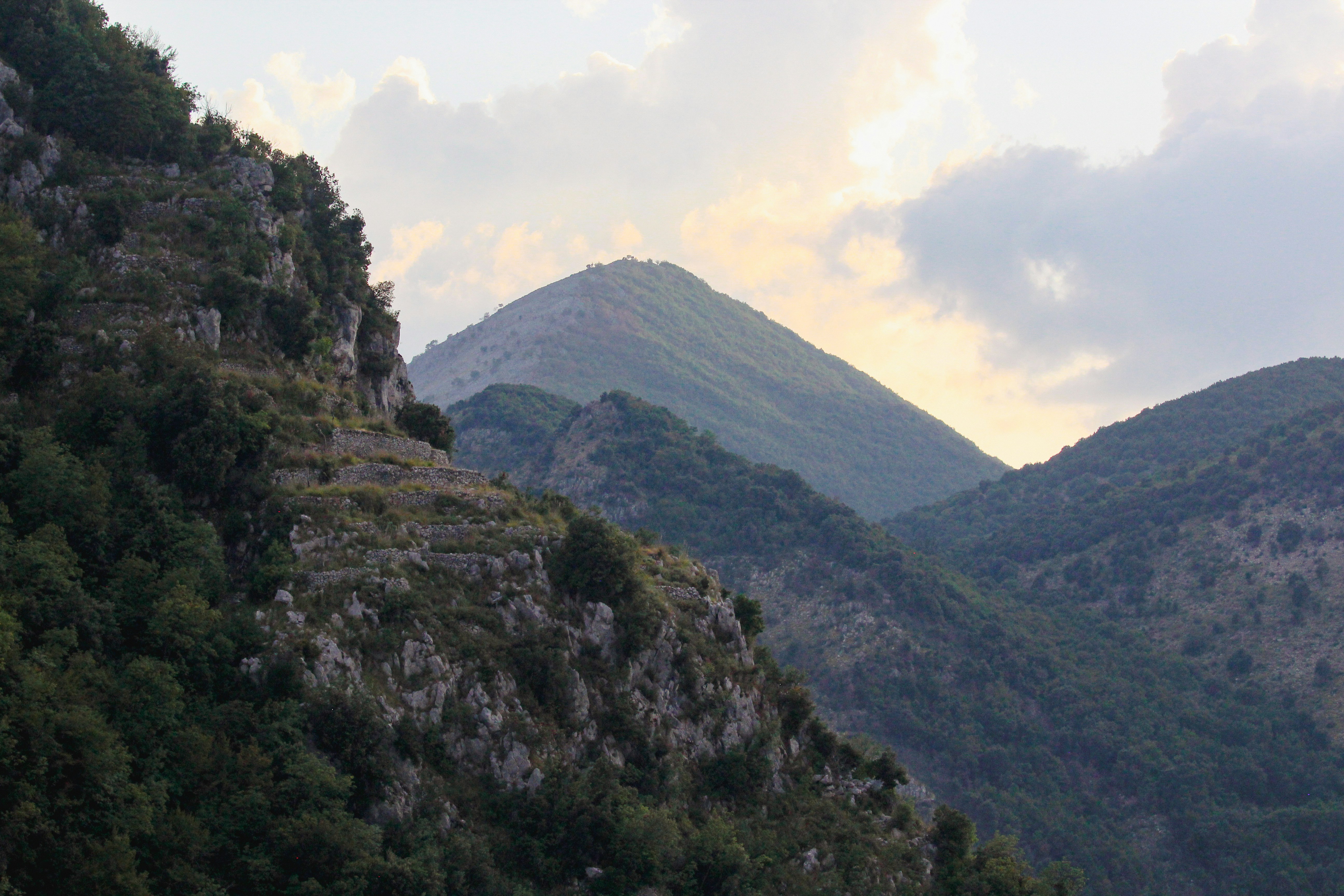 Green mountains under a cloudy sky at dusk.