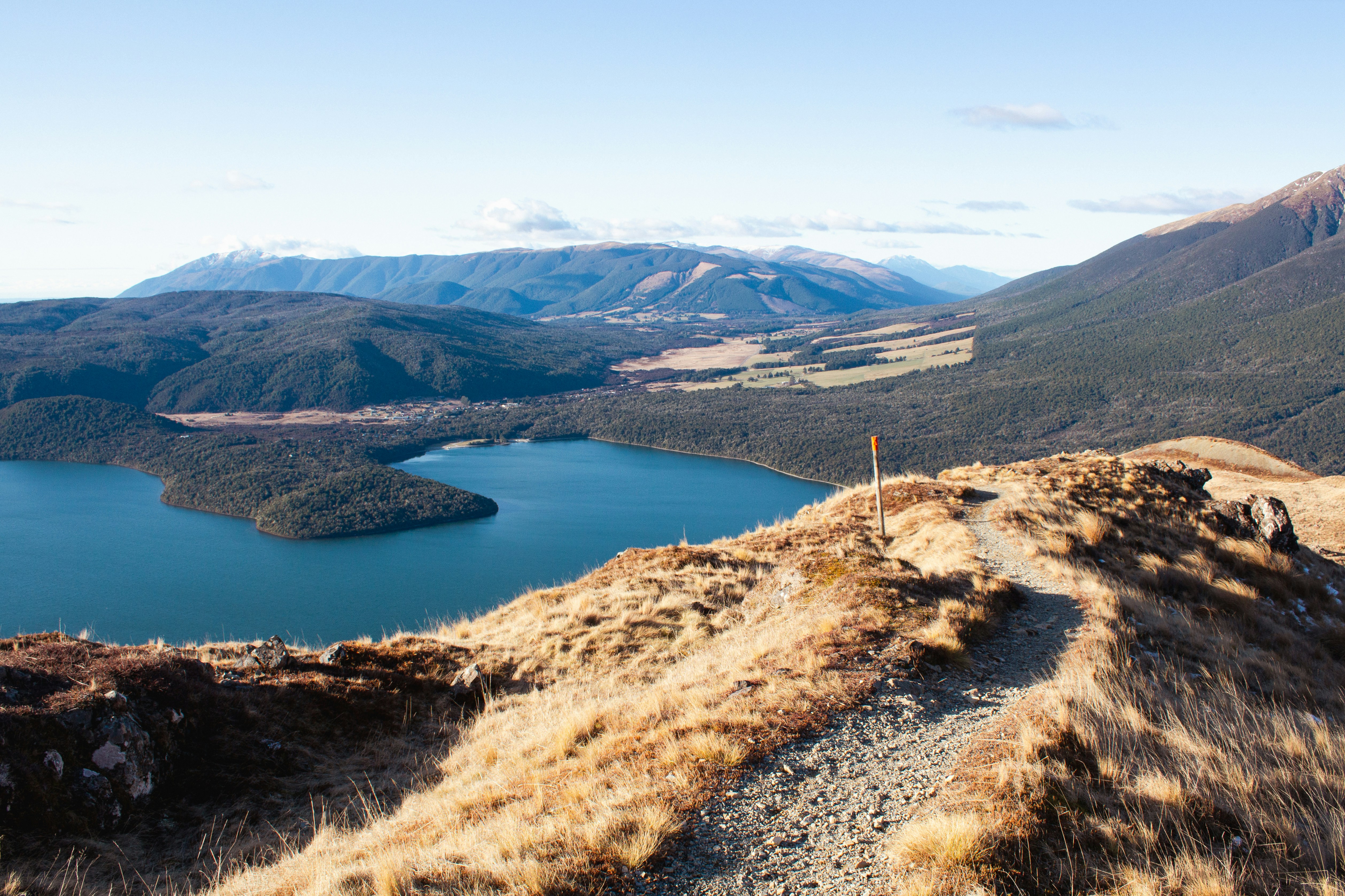 A winding path overlooks a blue lake and distant mountains