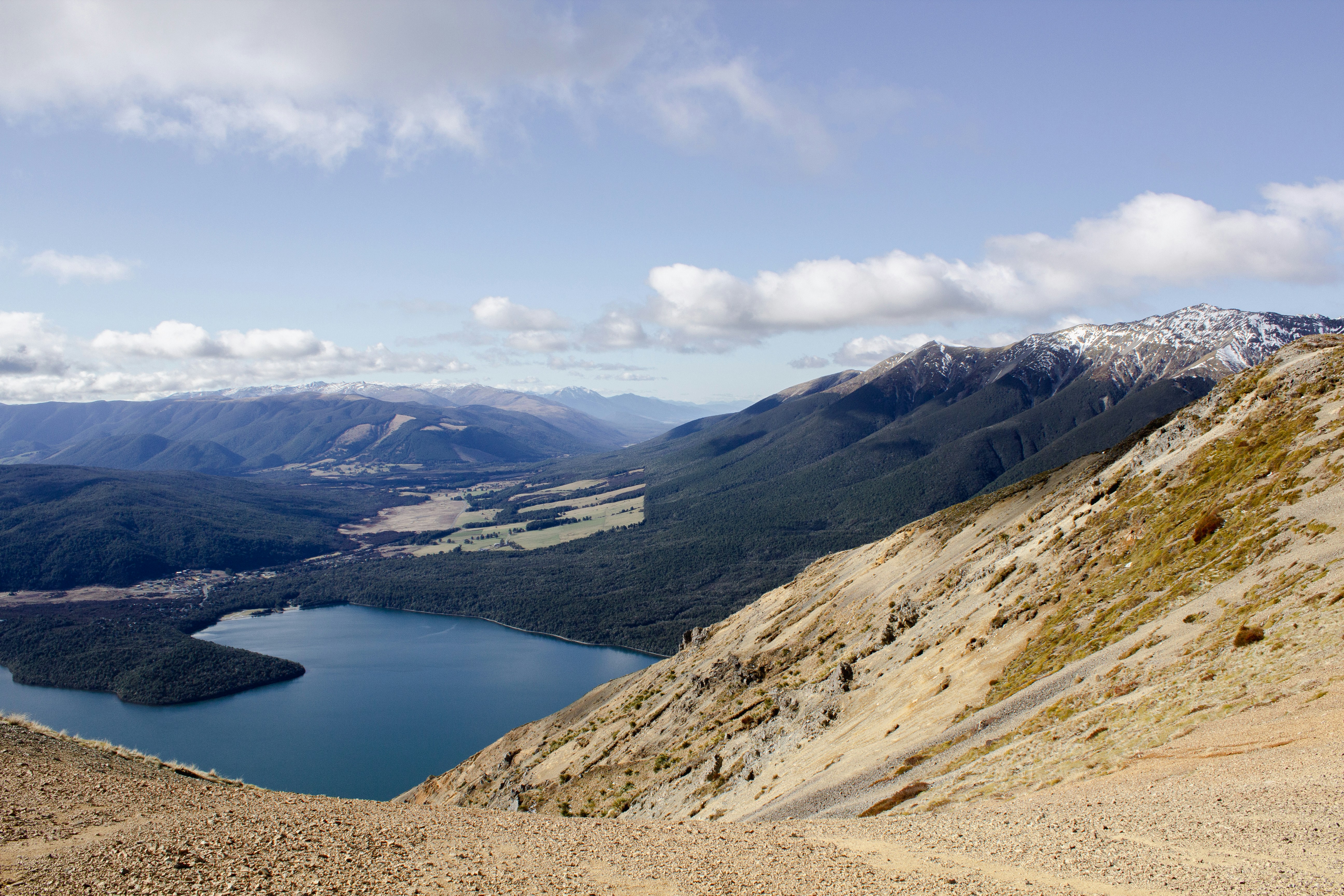 Steep mountain slope overlooking a serene lake and distant peaks