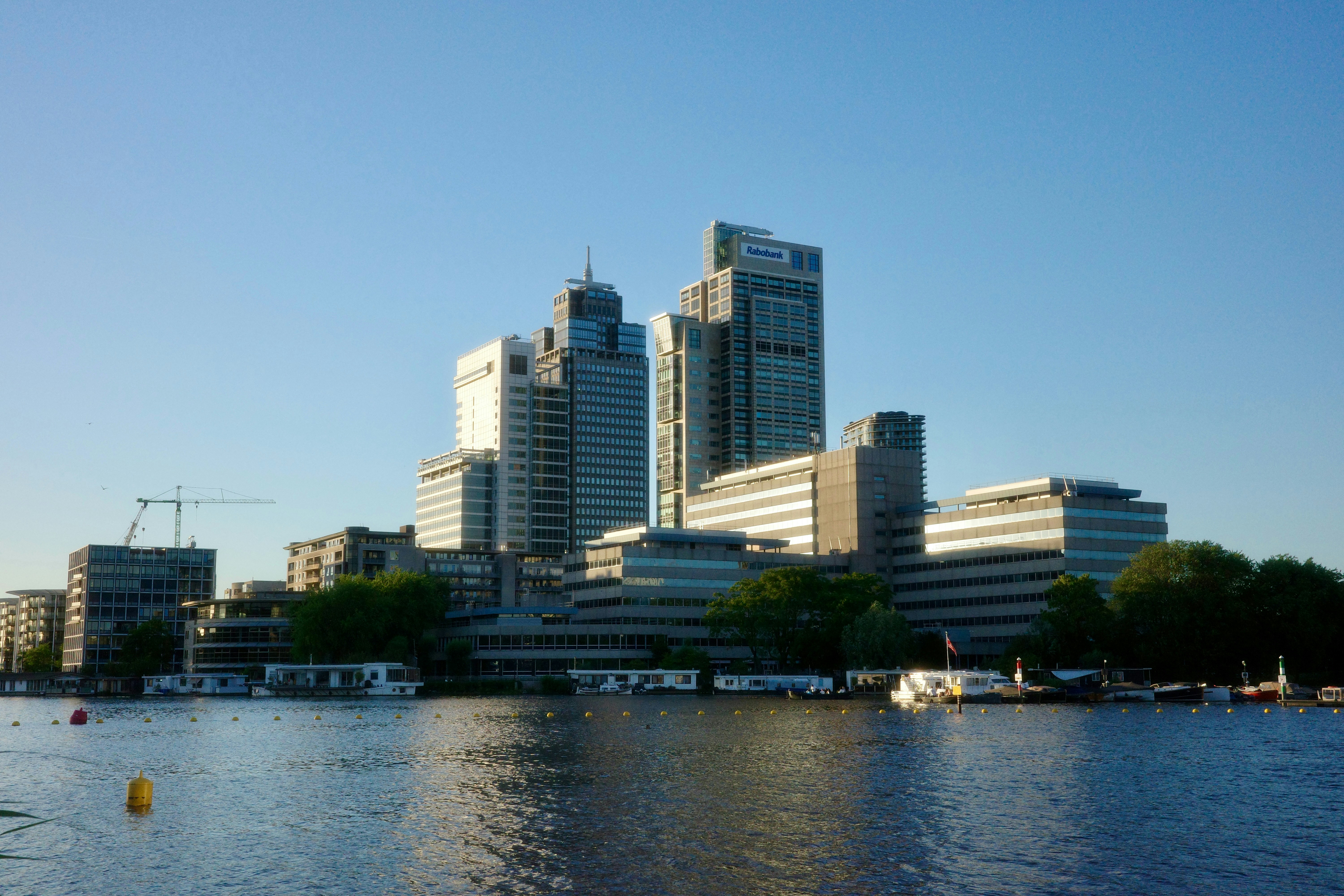Modern city buildings line the waterfront under a clear sky