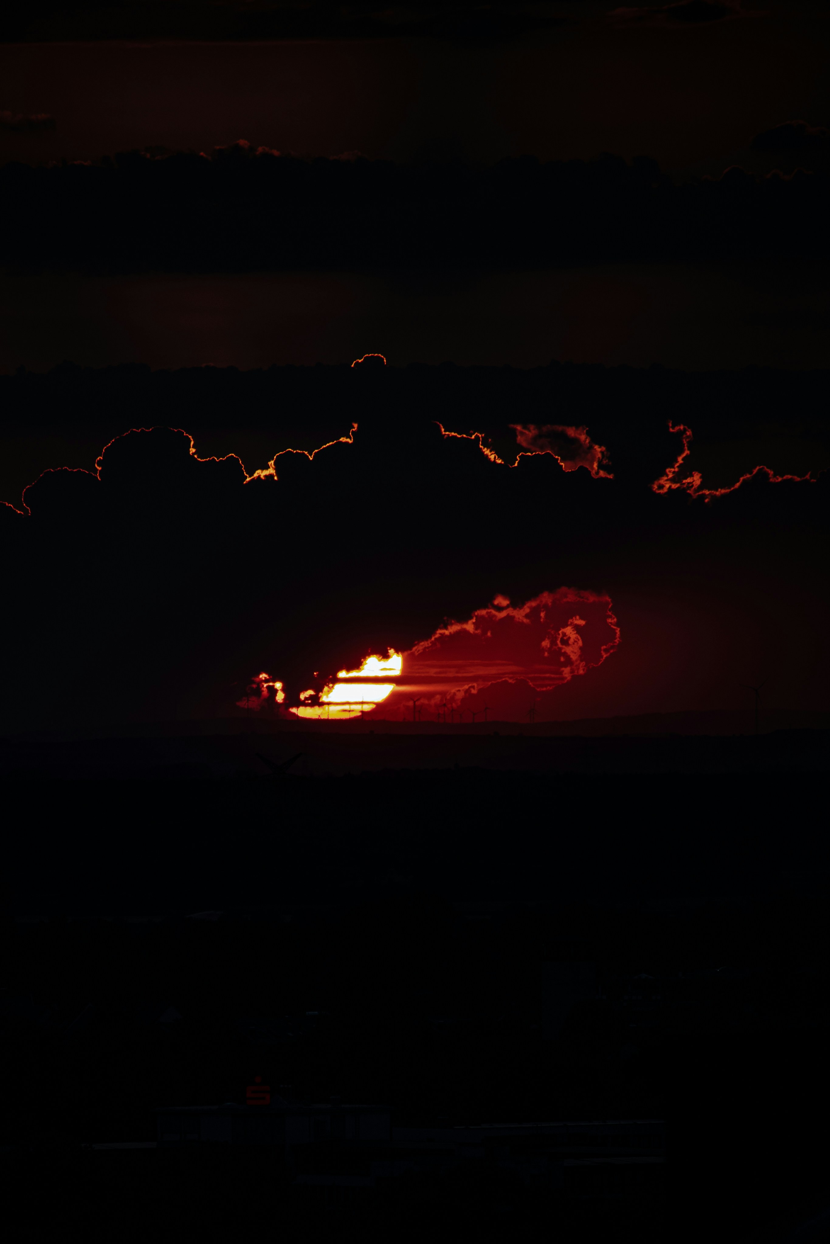 暗く燃える雲の間から太陽が顔を覗かせる劇的な夕焼け。の写真