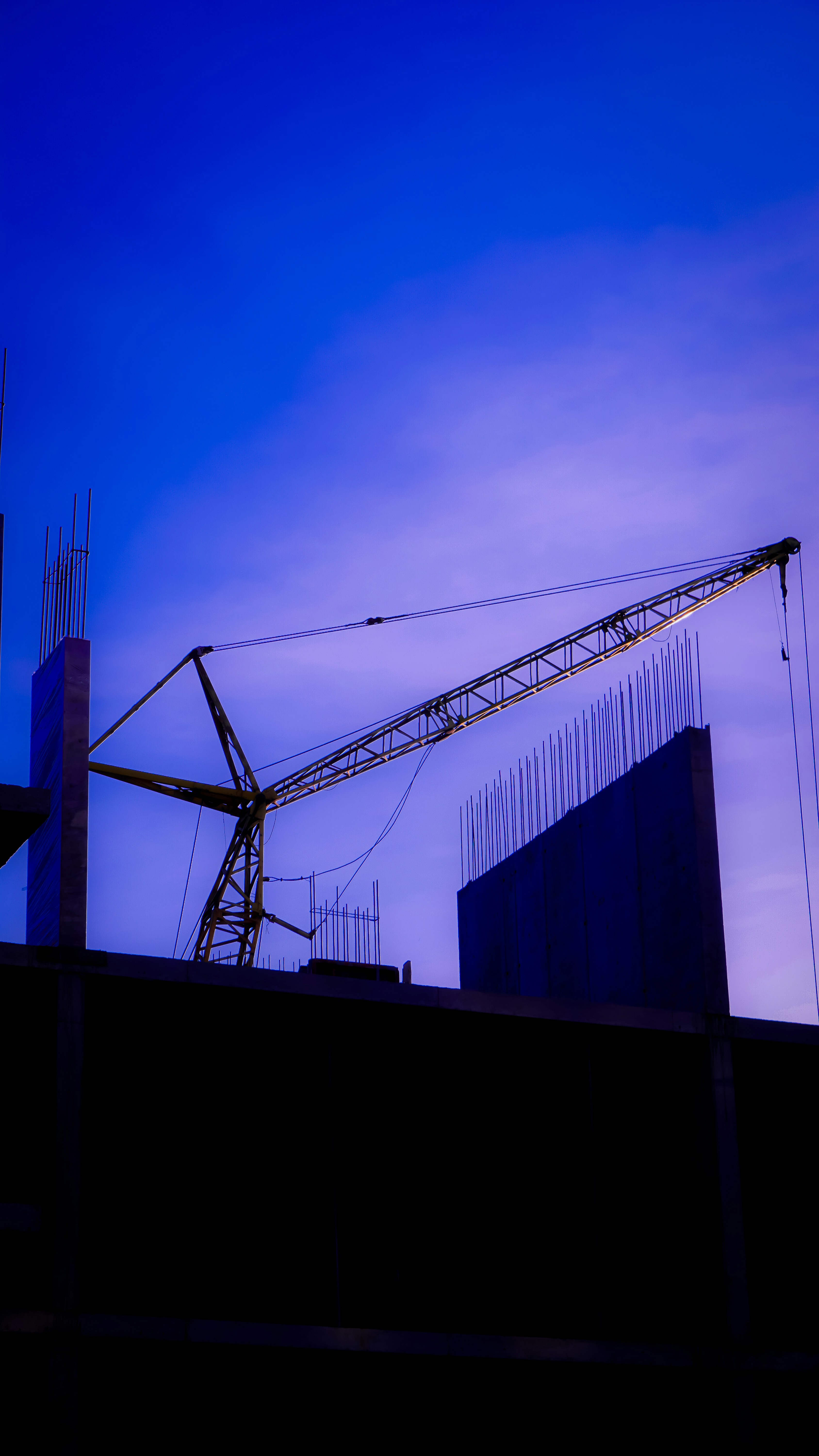Una gru da costruzione e la sagoma di un edificio contro un cielo azzurro.