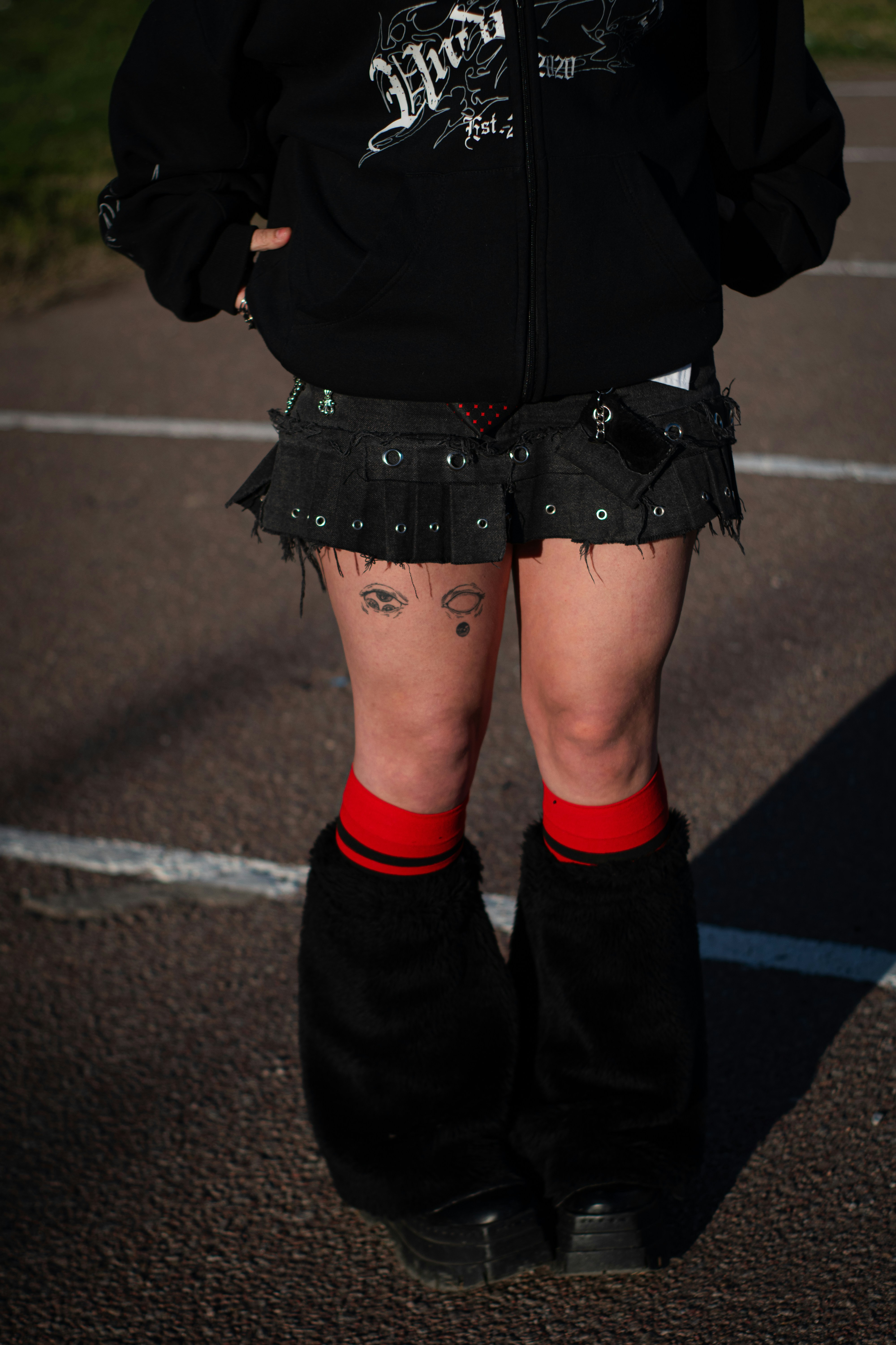 Person wearing dark clothing, red socks, and furry leg warmers.