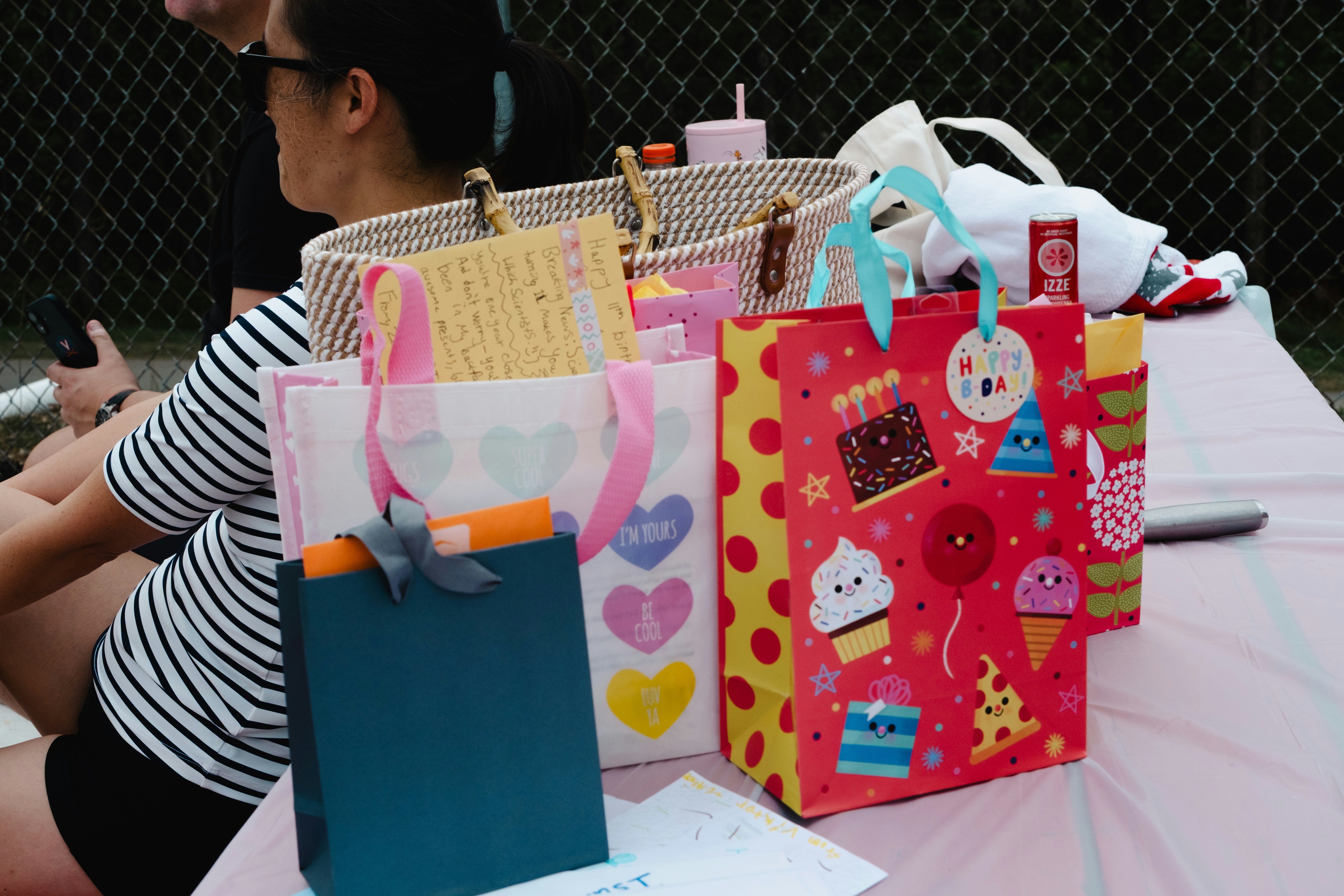 Sacolas de presente coloridas em uma mesa em um evento ao ar livre.