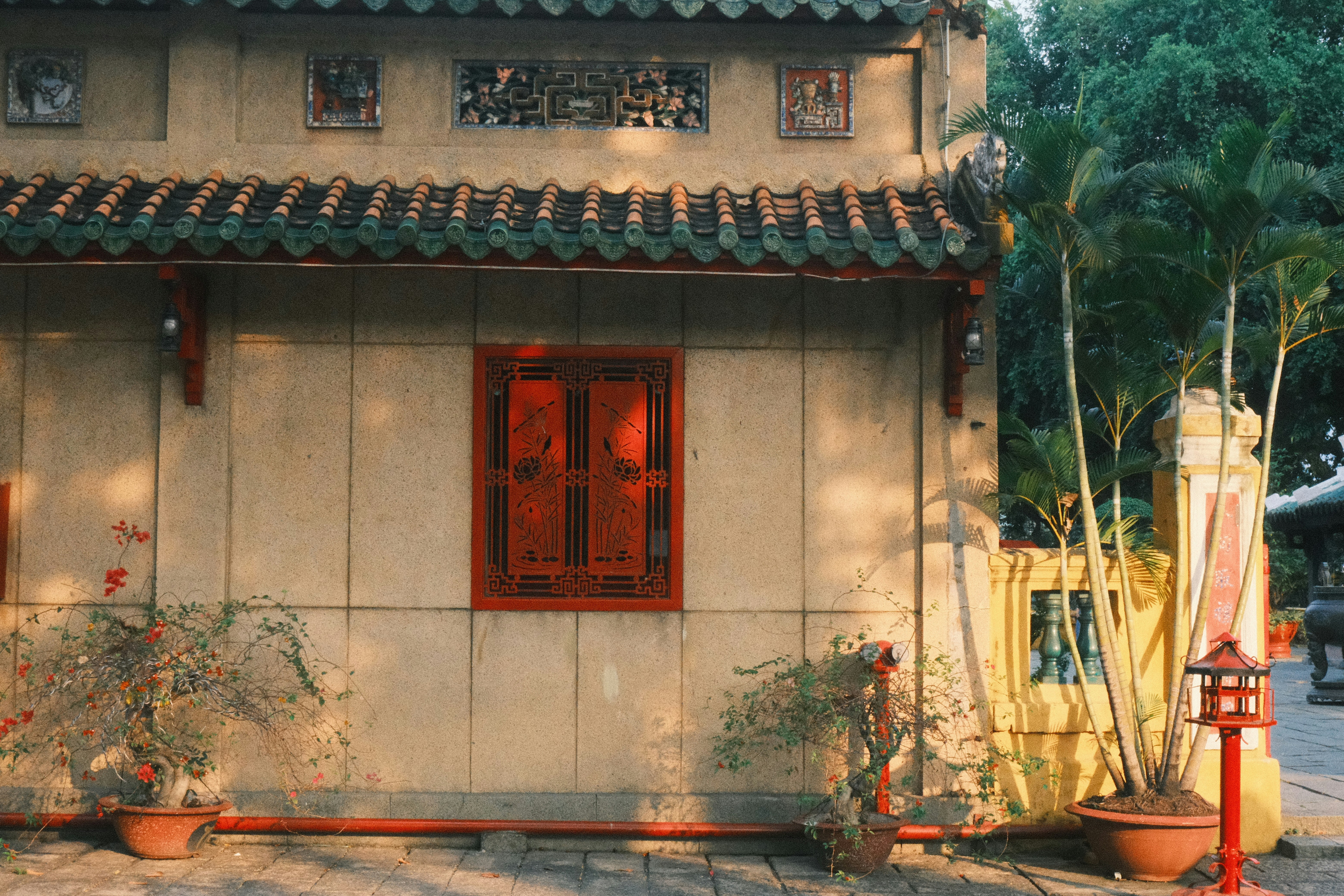 Traditional building with red window and green tiled roof.
