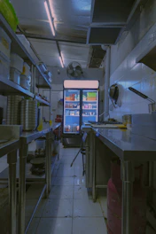 Stainless steel kitchen with a brightly lit commercial refrigerator