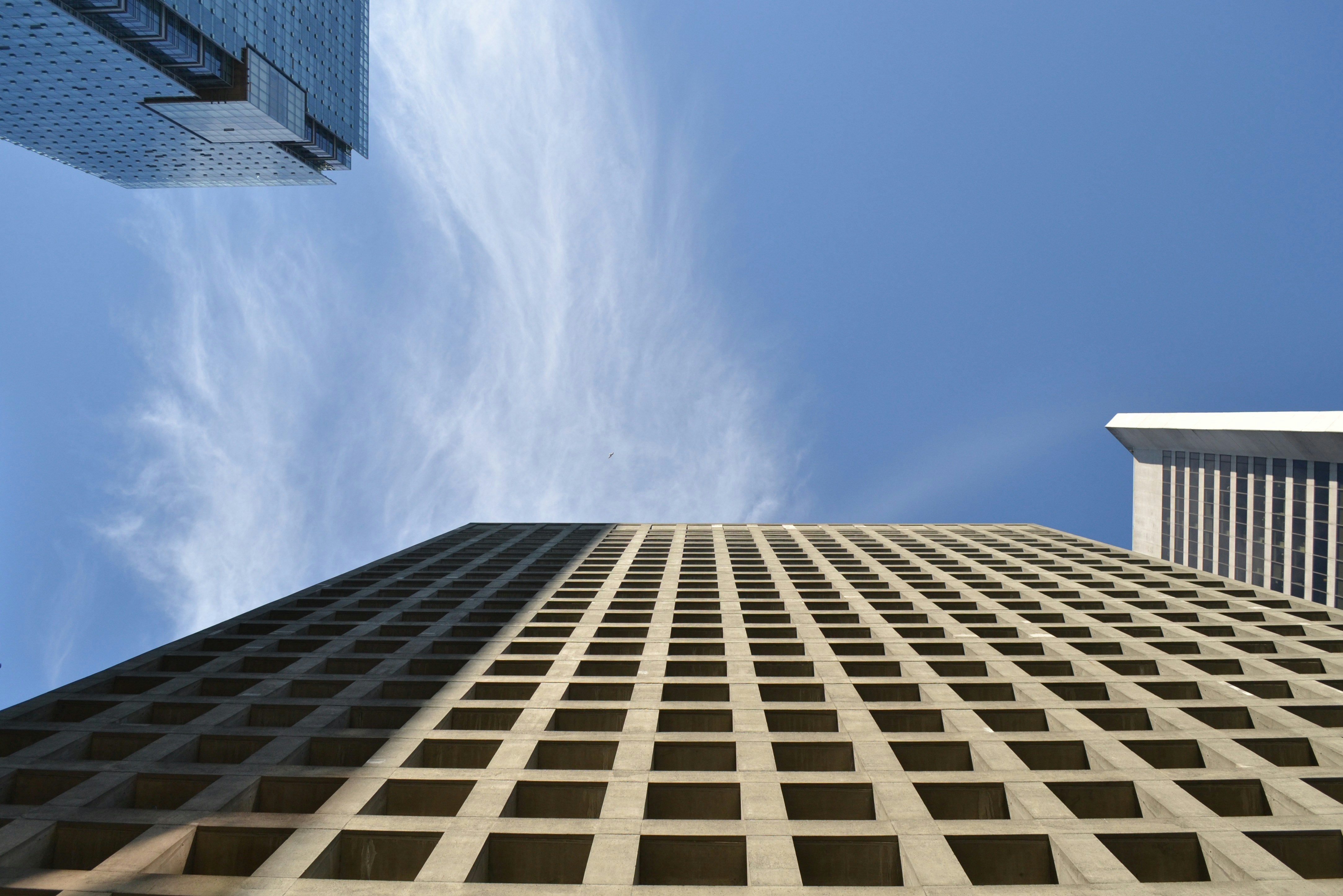 Modern skyscrapers reaching into a bright blue sky with clouds.