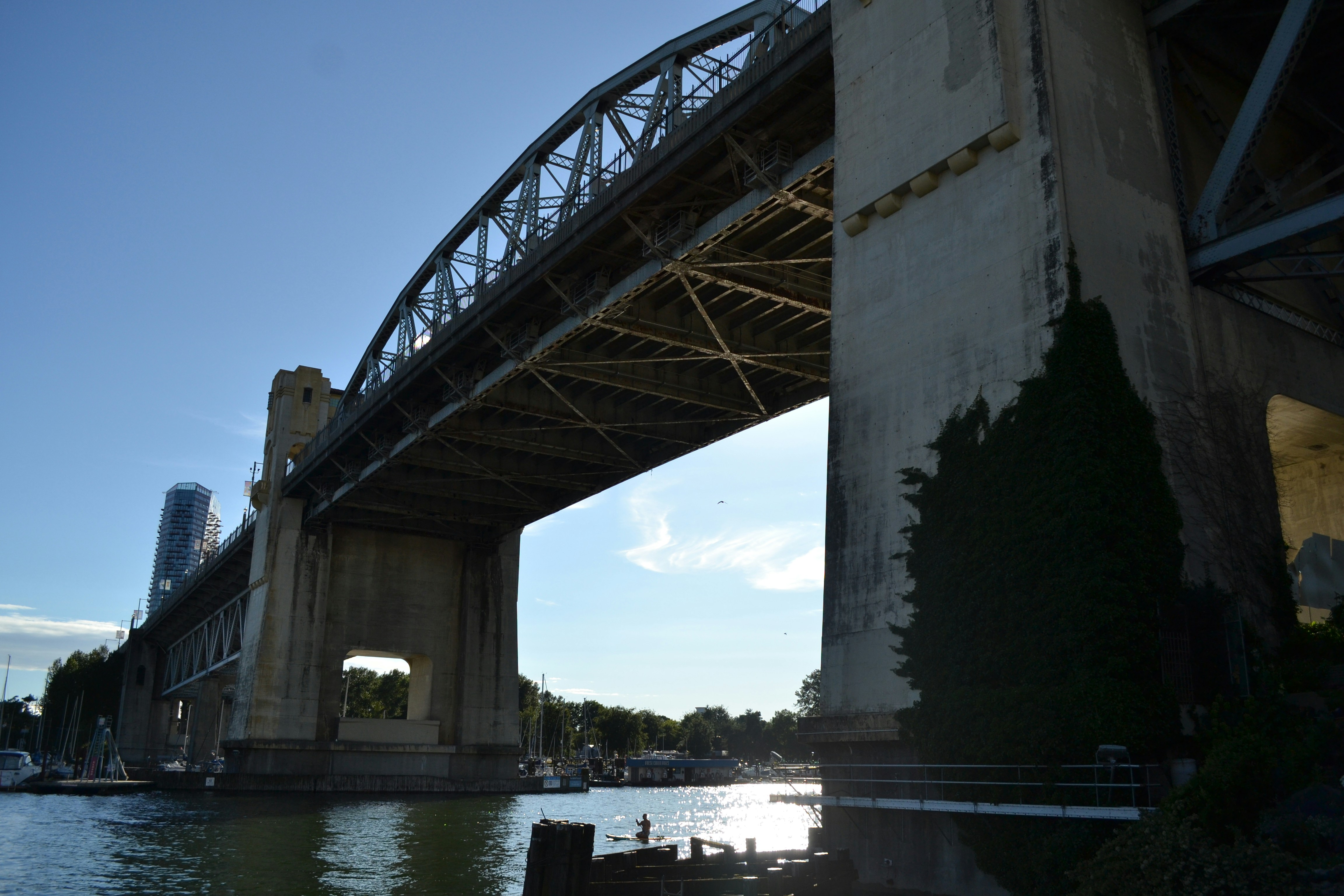 Concrete bridge spans over water against a bright blue sky.