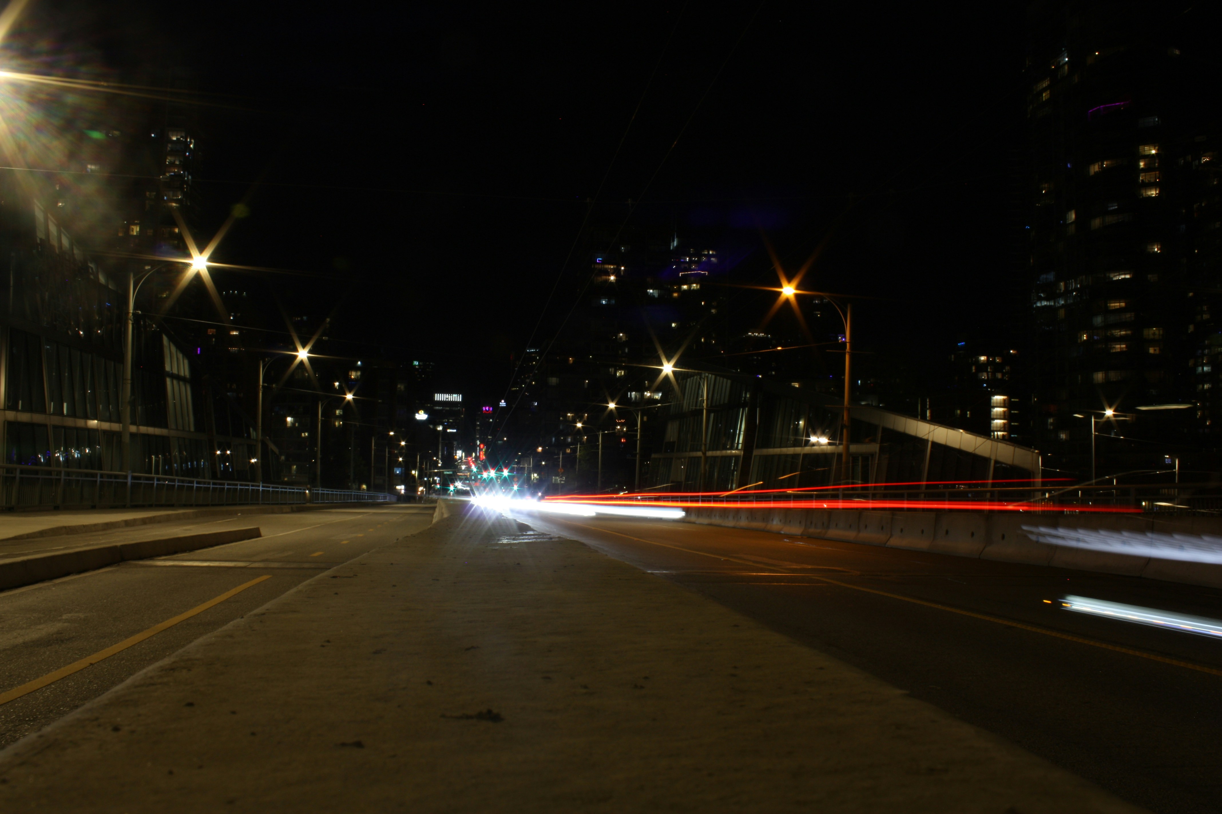 Night city street with car light trails and bright streetlights.