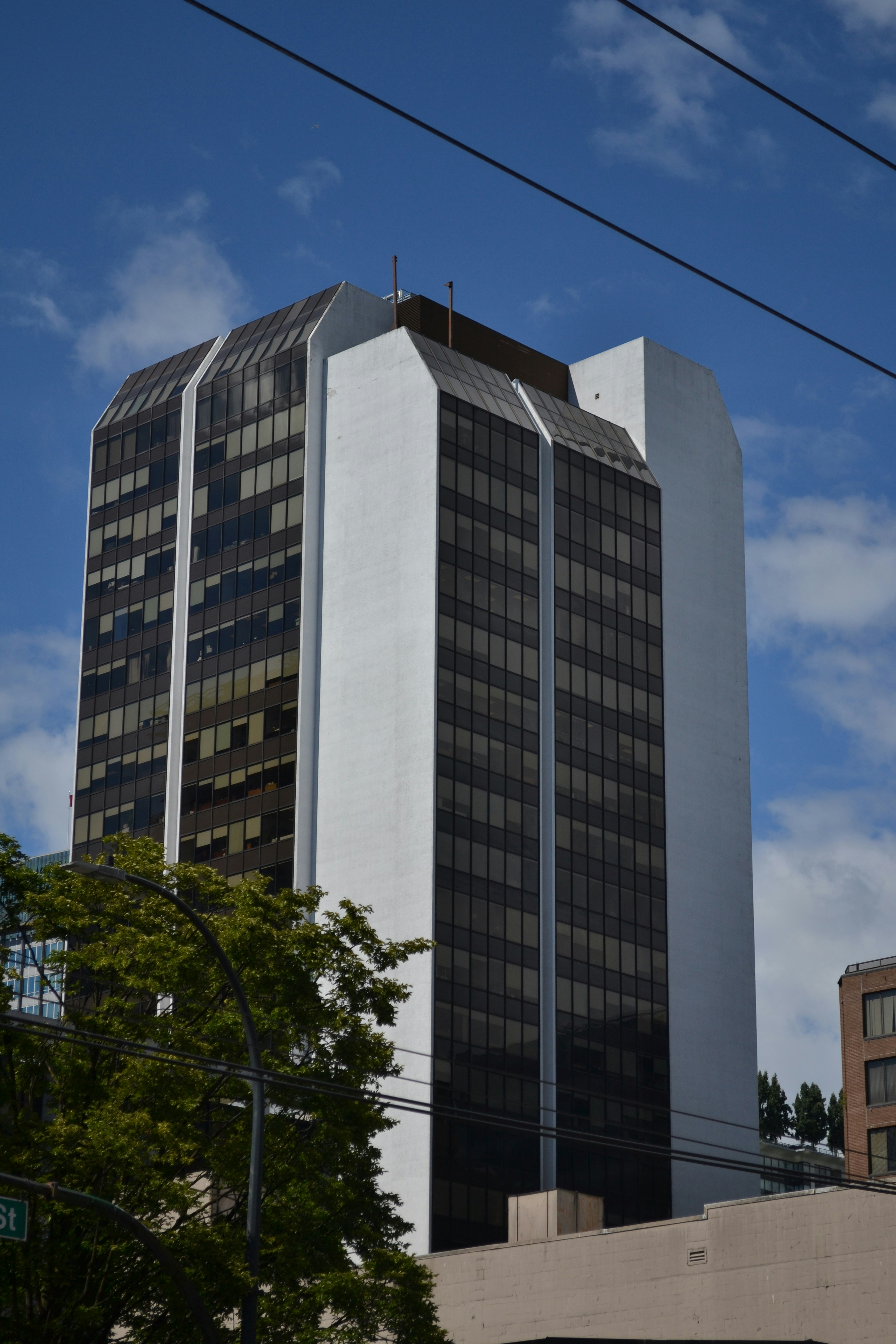 Modern high-rise building with dark windows under a blue sky.
