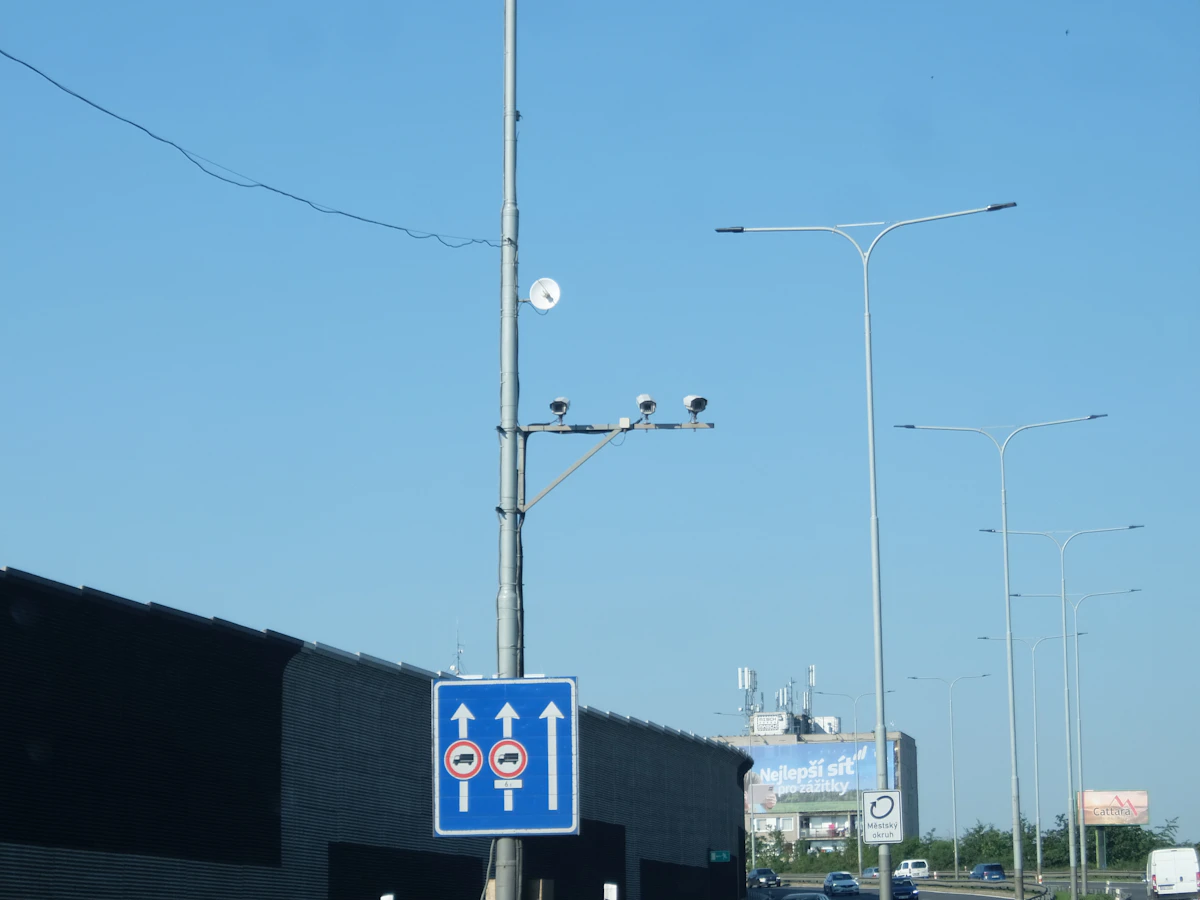 Kamera lalu lintas terpasang pada tiang bersama rambu jalan biru.