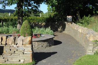 Outdoor memorial with stone walls and a winding path
