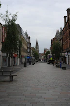 A quiet pedestrian street with buildings and a distant spire