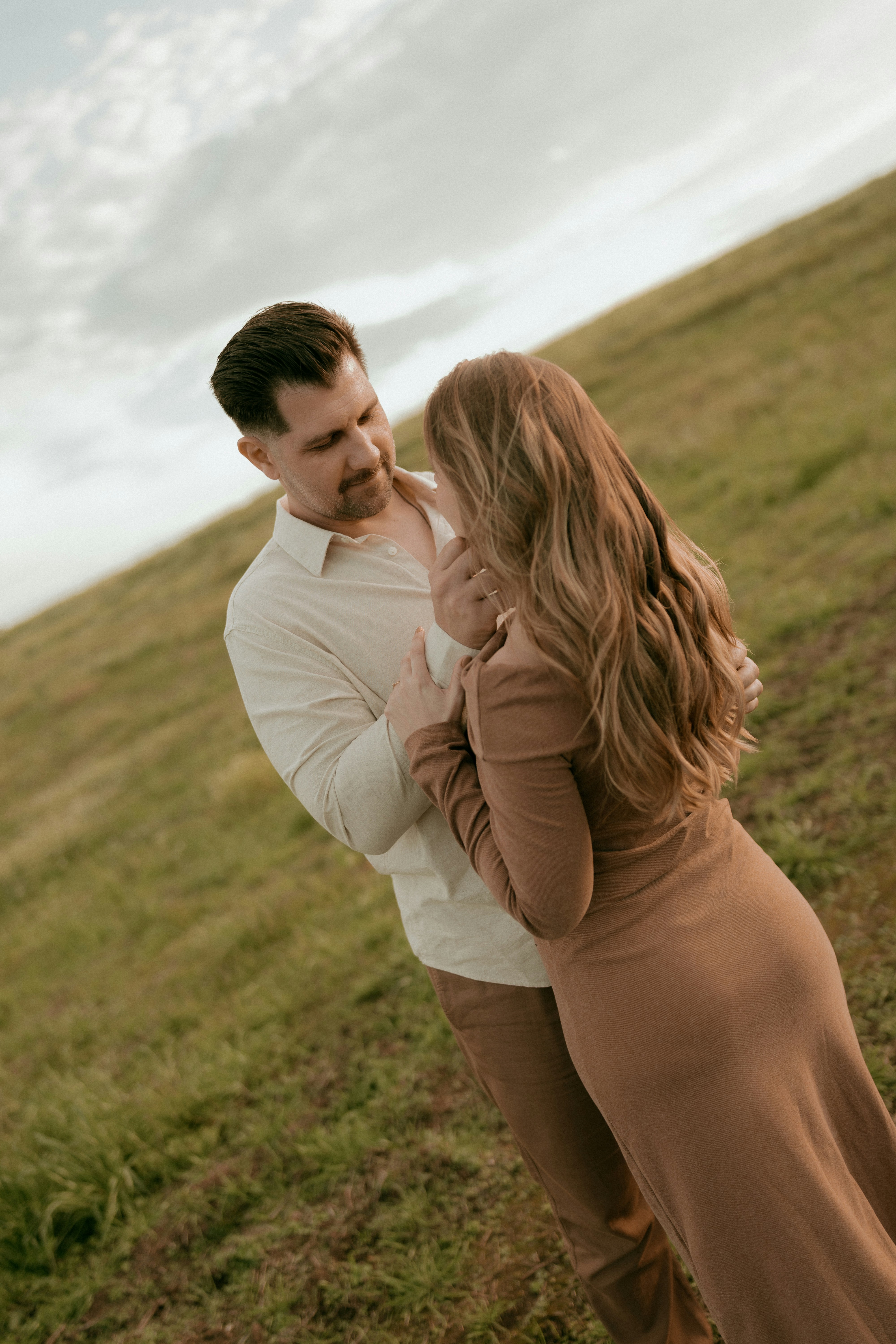 Young couple embracing on a grassy slope outdoors