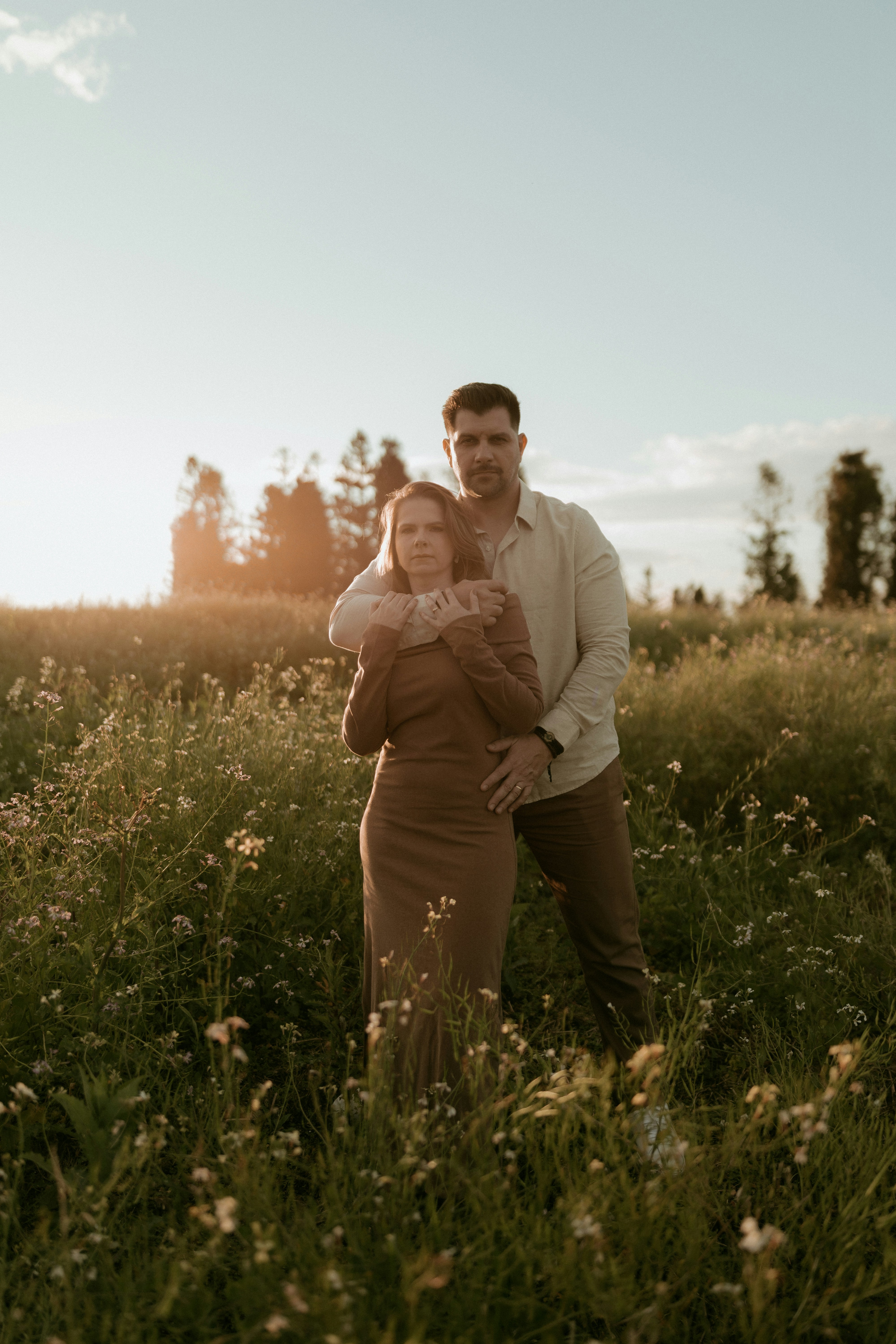 A couple embraces in a wildflower field at sunset