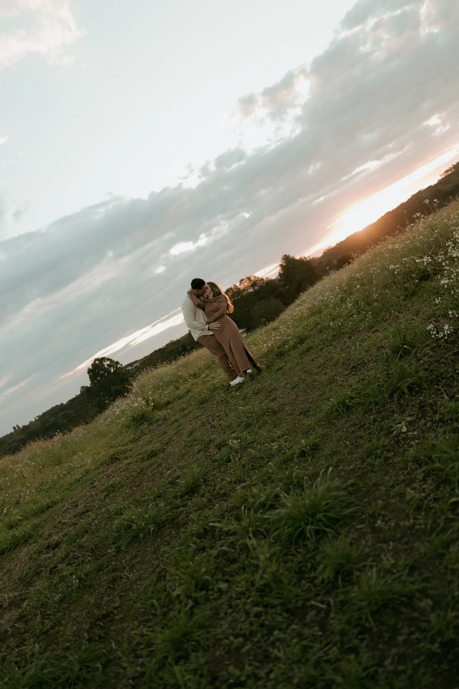Couple embracing on a hill at sunset