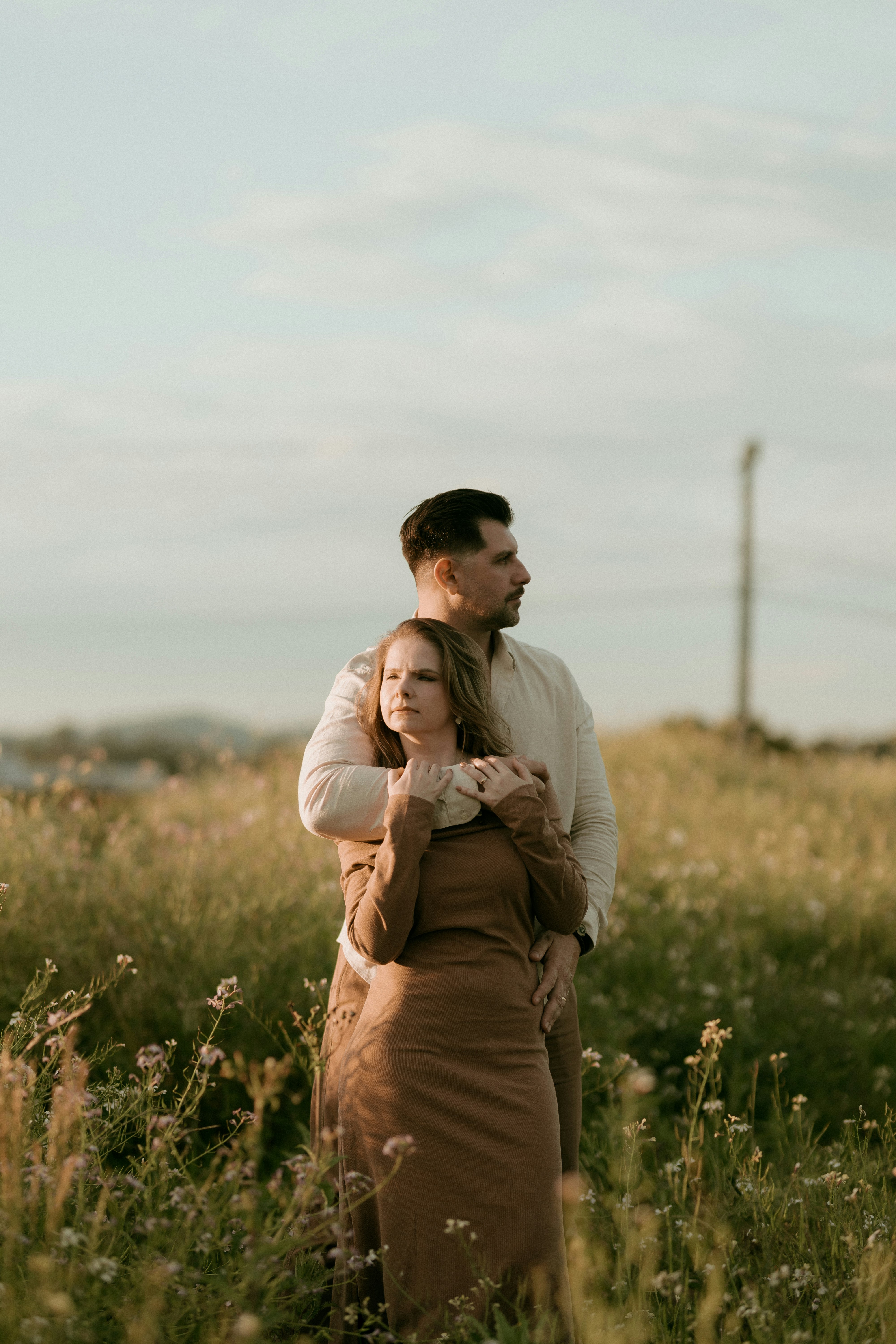 A couple embracing in a sunlit field of wildflowers