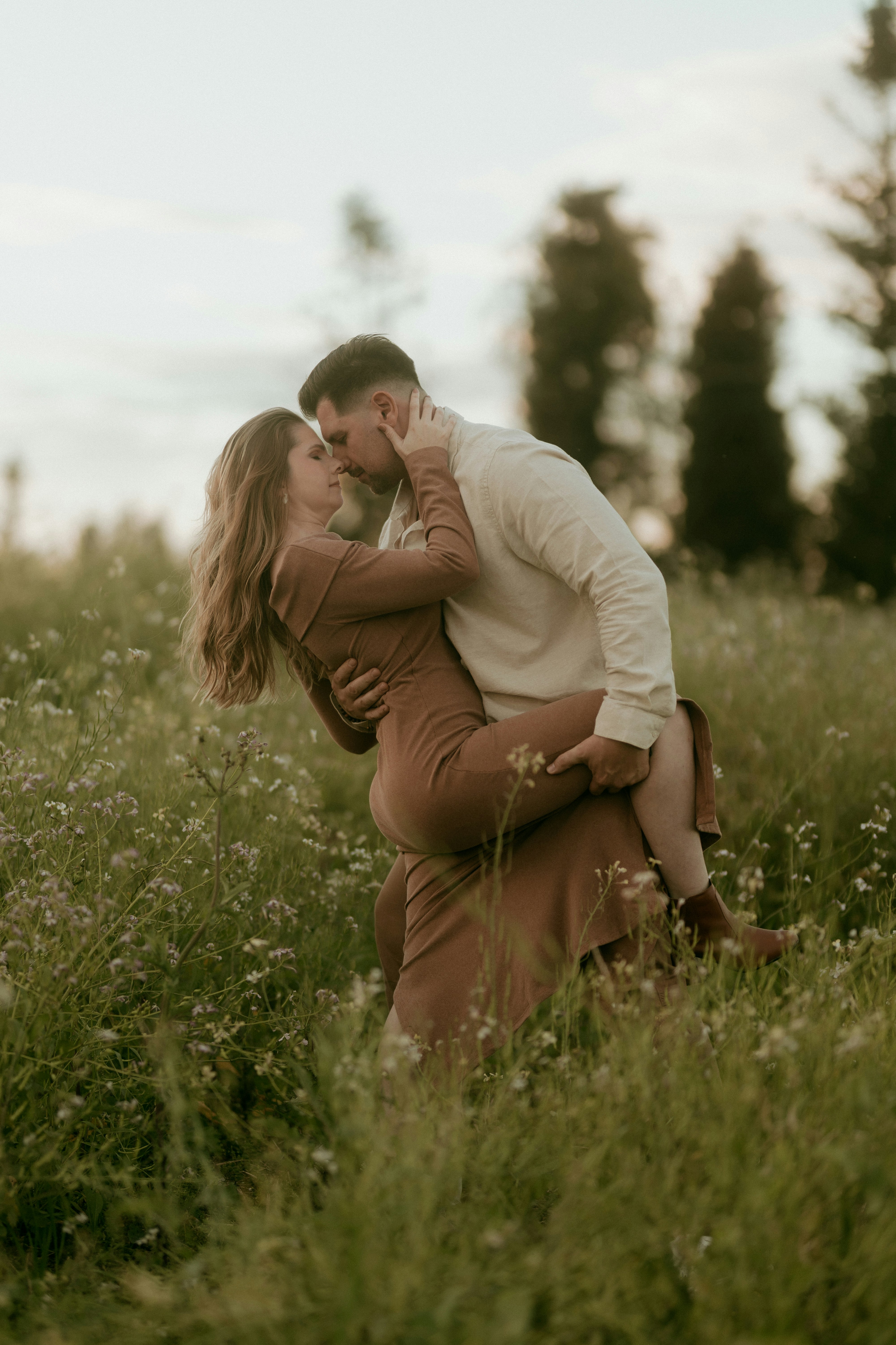 A romantic couple embraces in a field of wildflowers