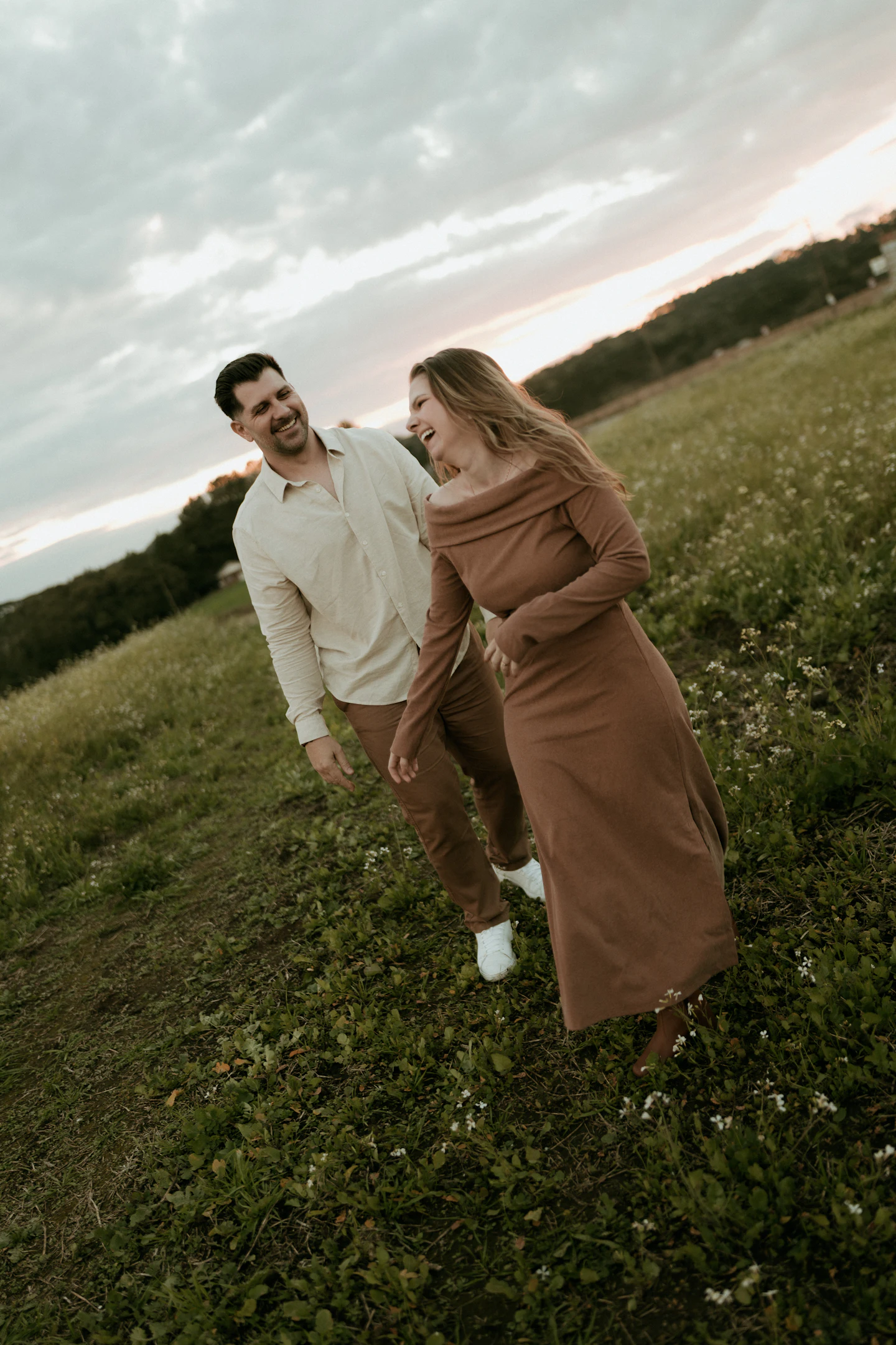 A couple walking through wildflowers at sunset