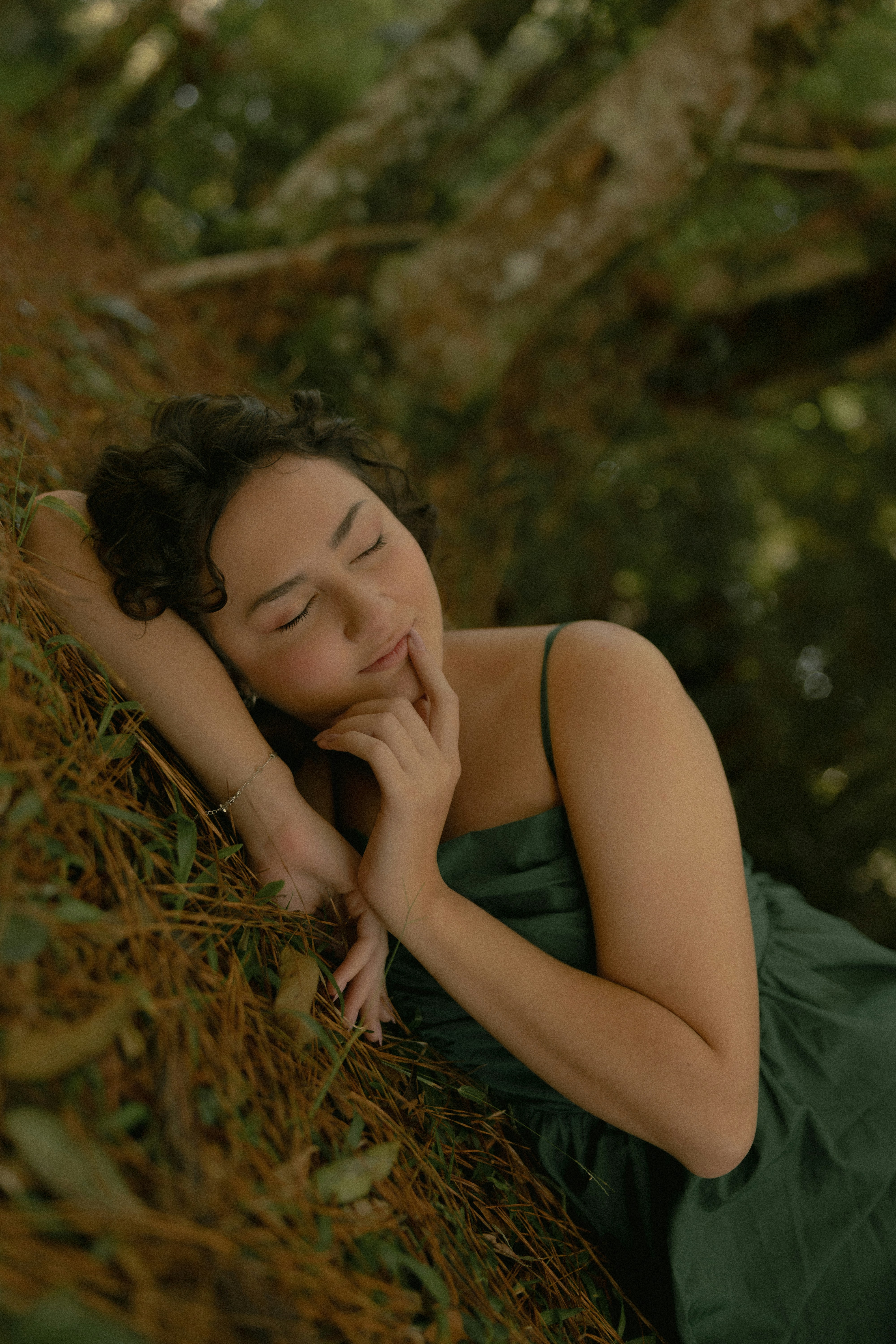 Serene woman in green dress resting on forest ground