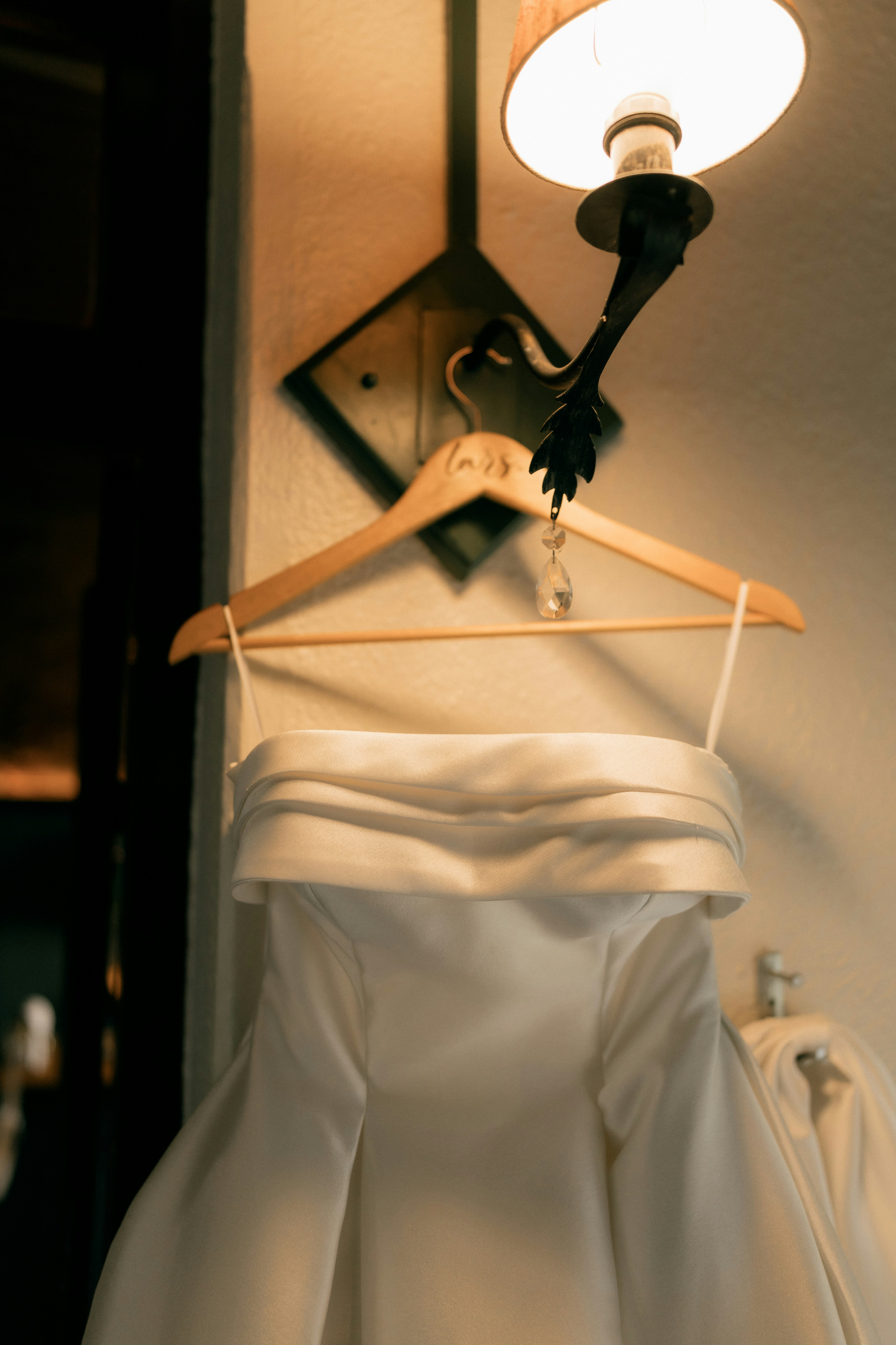 White Off-The-Shoulder Dress Hanging From A Wall Light Fixture.