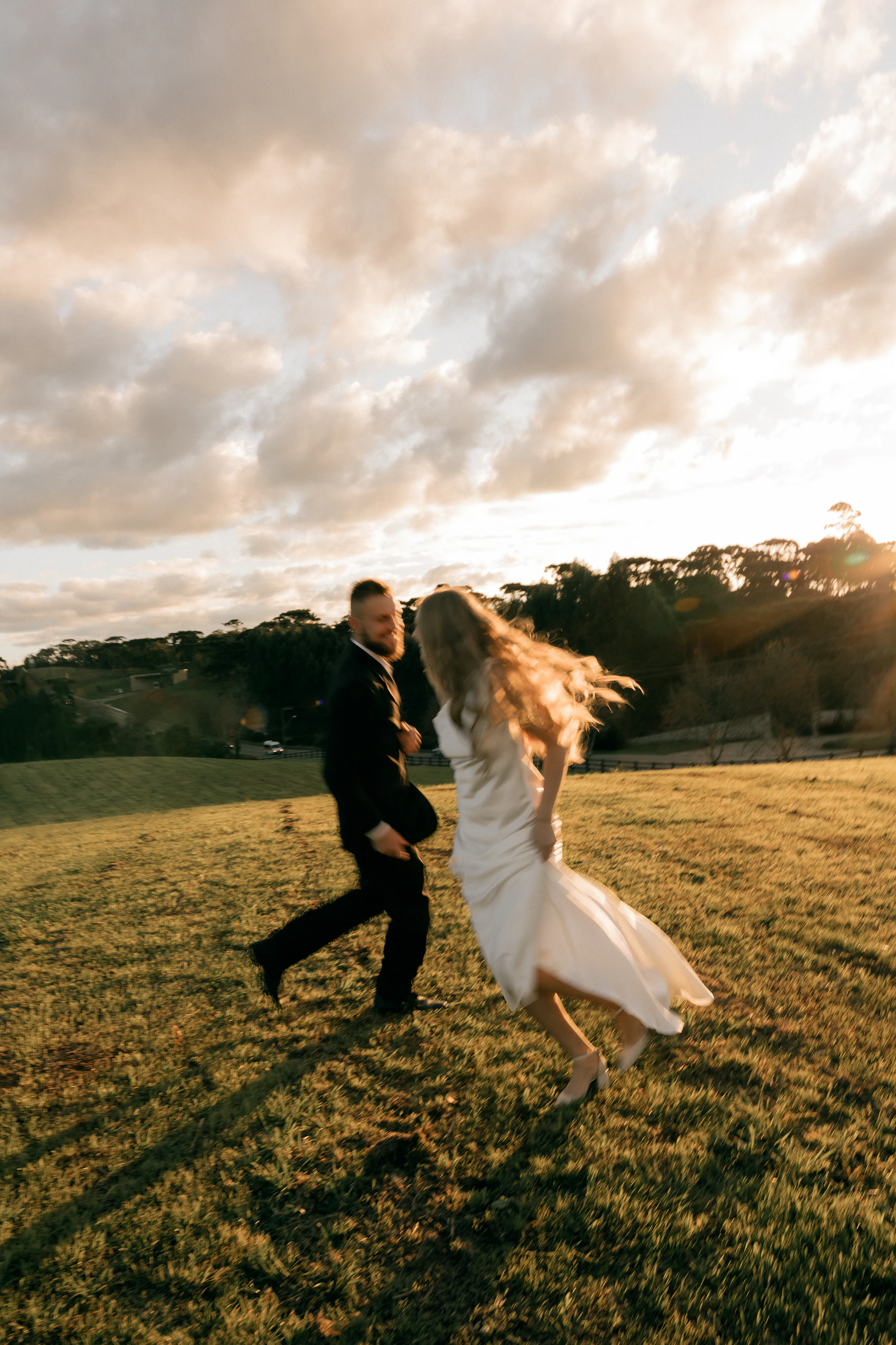 Newlyweds running across a sunlit field