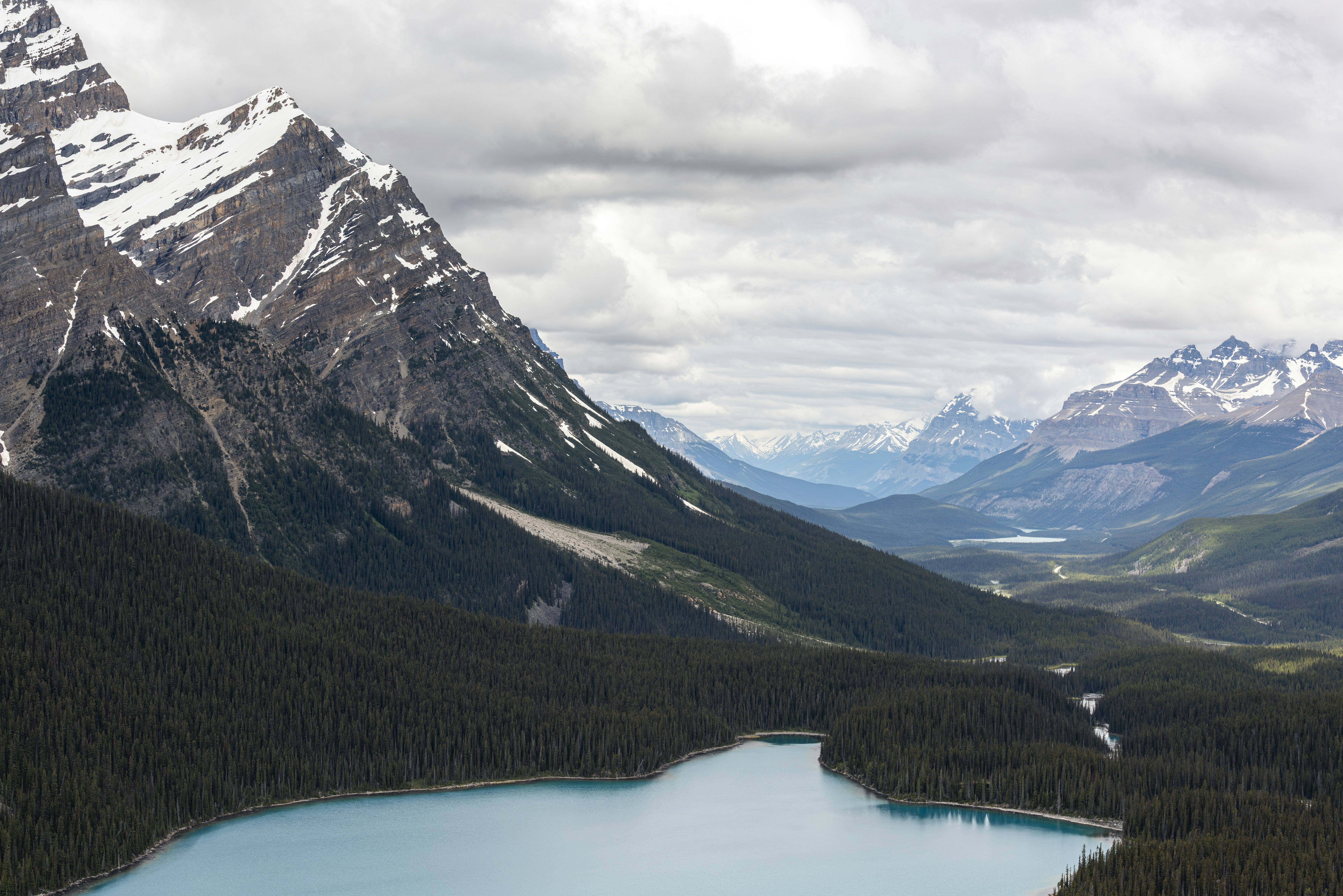 Turquoise lake nestled among snow-capped mountains and green pine forests