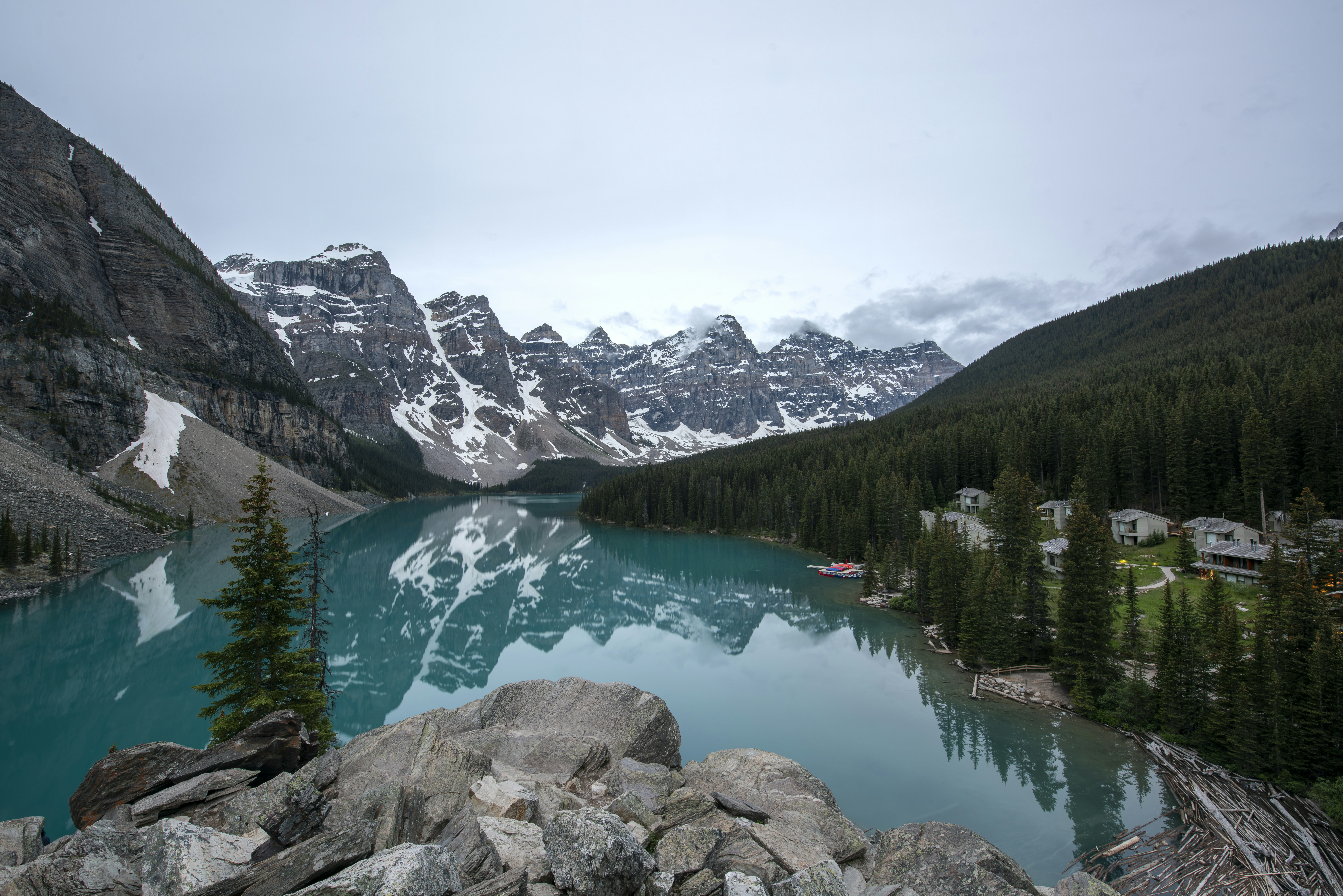 Turquoise lake reflecting snow-capped mountains and pine forests