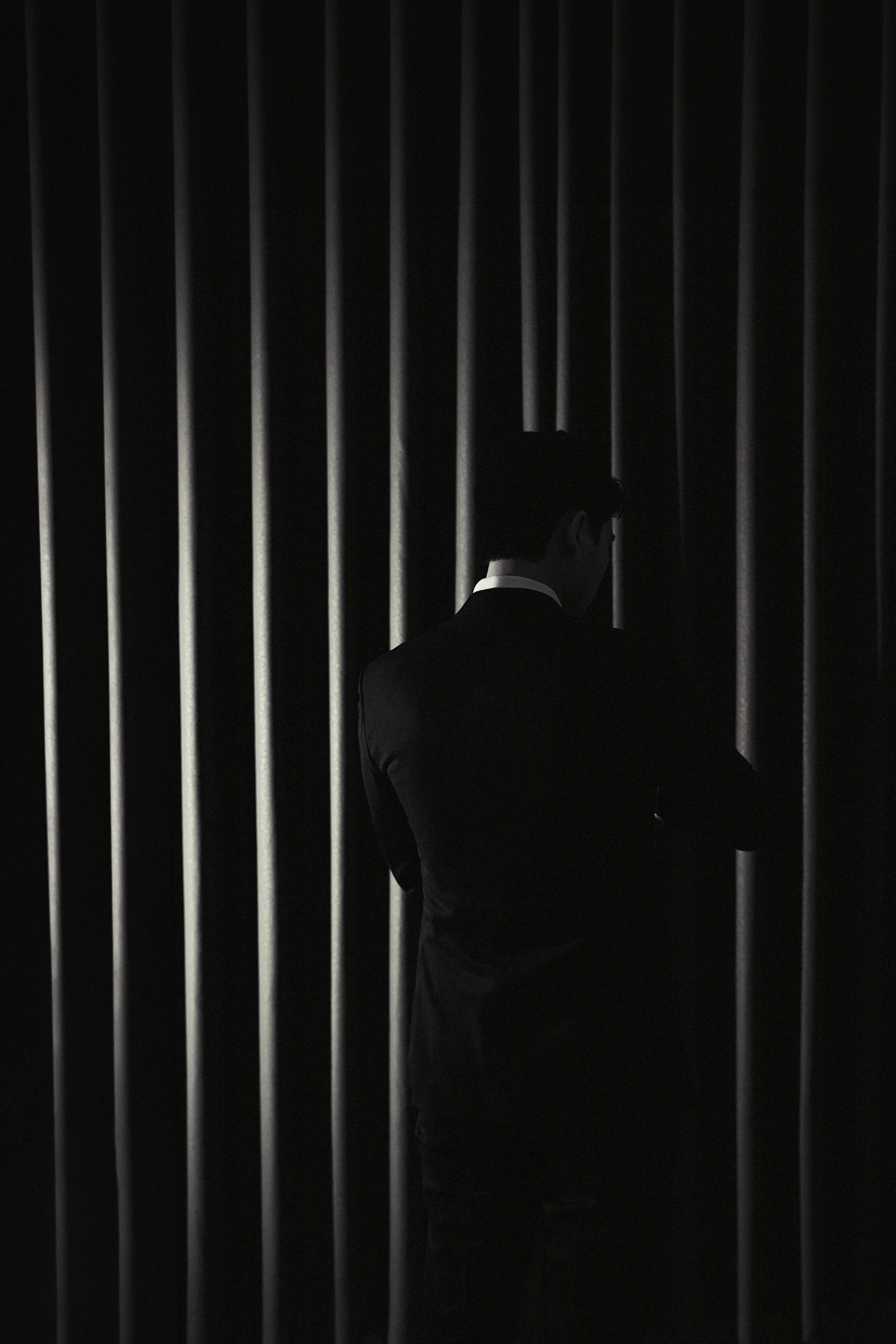Man in a black suit photographed in dramatic editorial light