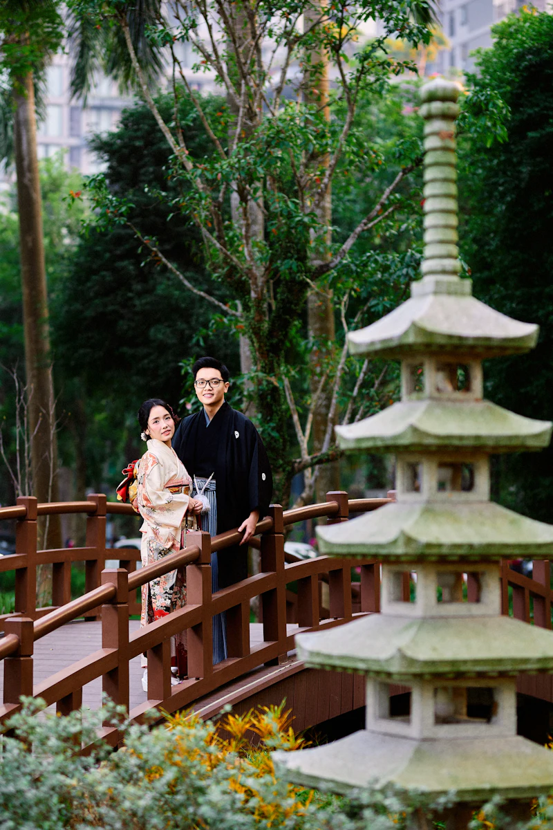 A couple in traditional Japanese attire on a garden bridge